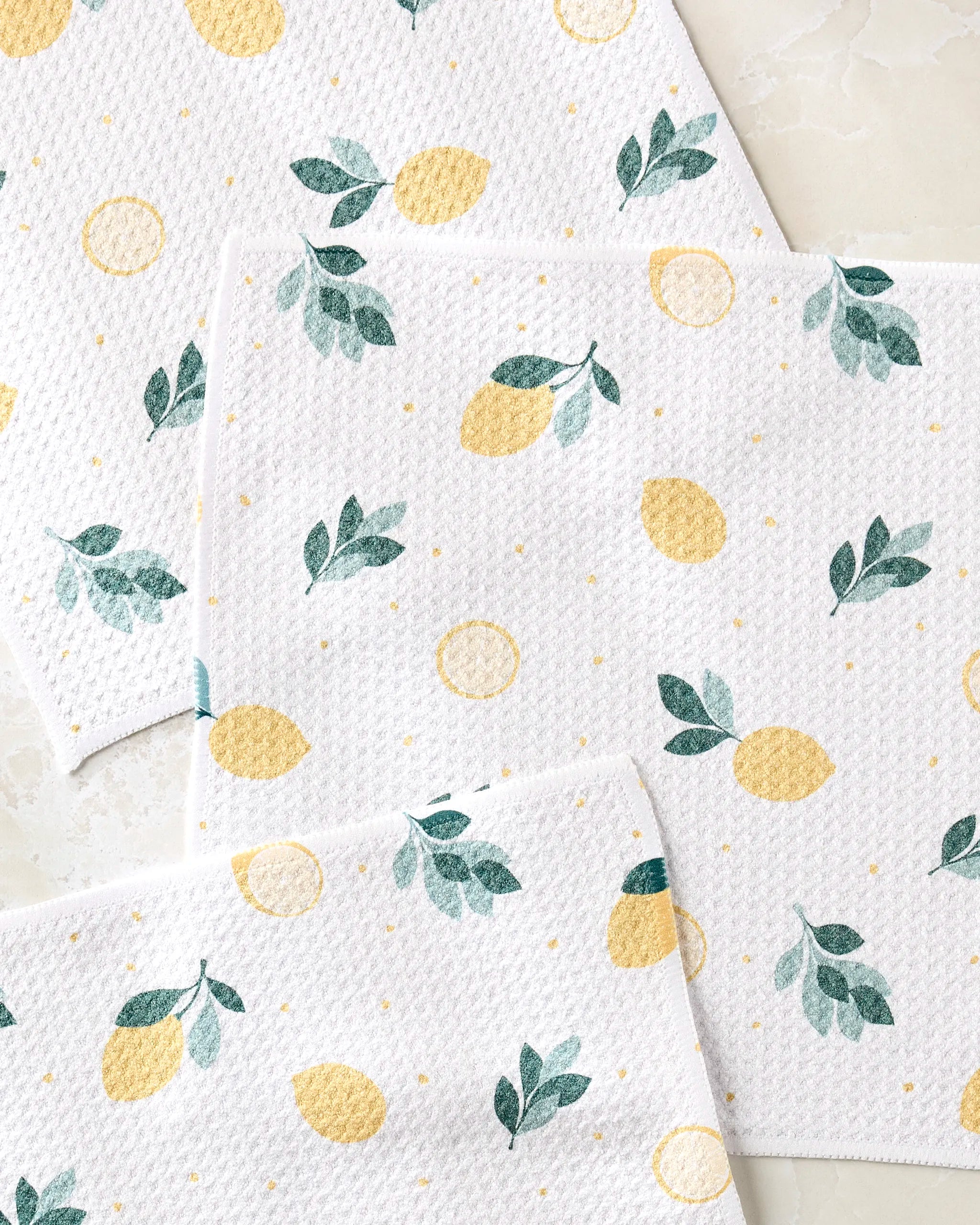 Freshly Picked by Sara Mari: White textured, super-absorbent dishtowels with a cheerful pattern of yellow lemons, lemon slices, green leaves, and dots on a light background.
