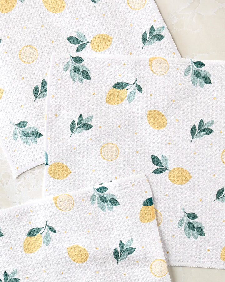 Freshly Picked by Sara Mari: White textured, super-absorbent dishtowels with a cheerful pattern of yellow lemons, lemon slices, green leaves, and dots on a light background.