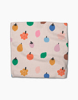 Fruit Basket by Jennifer Bouron is a textured beige dishcloth made from recycled materials, featuring a scattered design with colorful fruit and leaf shapes in orange, yellow, green, blue, pink, and brown.