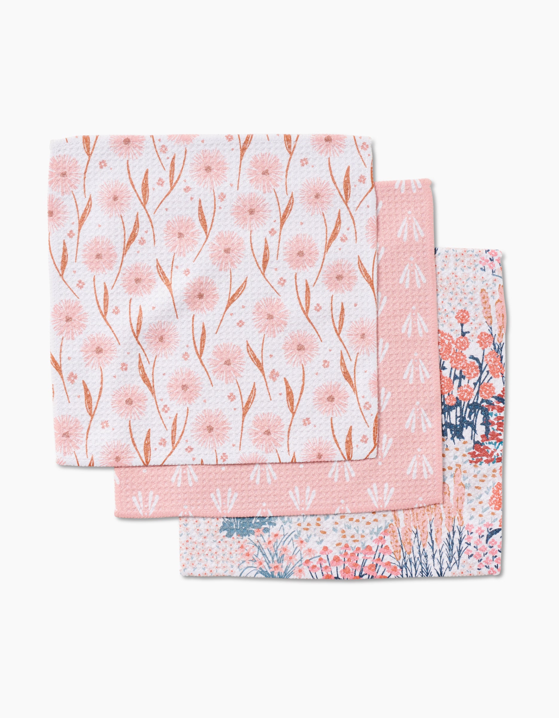 Three Garden Bloom dishcloths by Hufton Studio, made from Geoweave fabric, feature floral and geometric patterns in pink, white, and blue, and are arranged in a staggered stack.