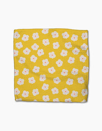 The Sara Mari Garden Crush blanket, crafted from recycled materials, features a yellow textured design with a repeating pattern of white flowers with pink centers and is shown flat on a white background.