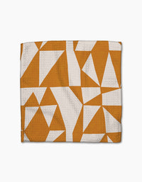 The Golden Angles towel by Lisa Nelson features a white and orange-brown geometric triangle pattern on textured fabric, crafted from recycled materials for super-absorbency and eco-friendly appeal.