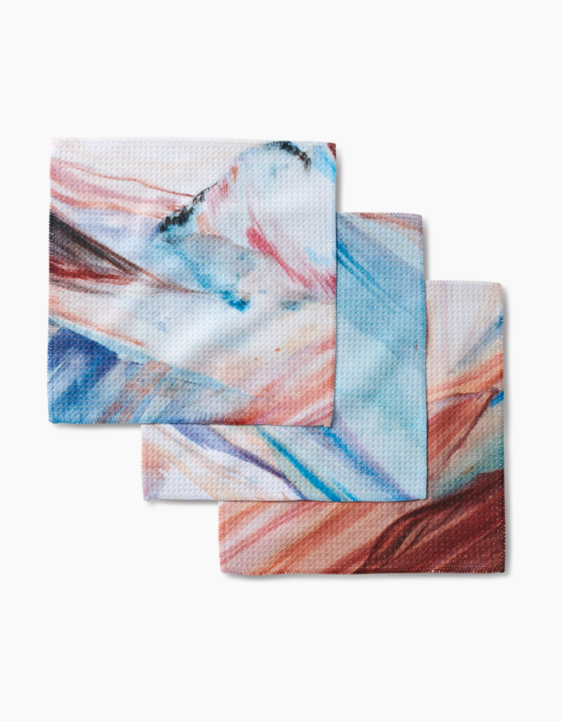Three square dishcloths from Kelly Peters, called Golden Hour in the Rockies, feature an abstract watercolor design in blue, pink, orange, and white. Made with innovative Geoweave fabric for excellent absorbency and durability.