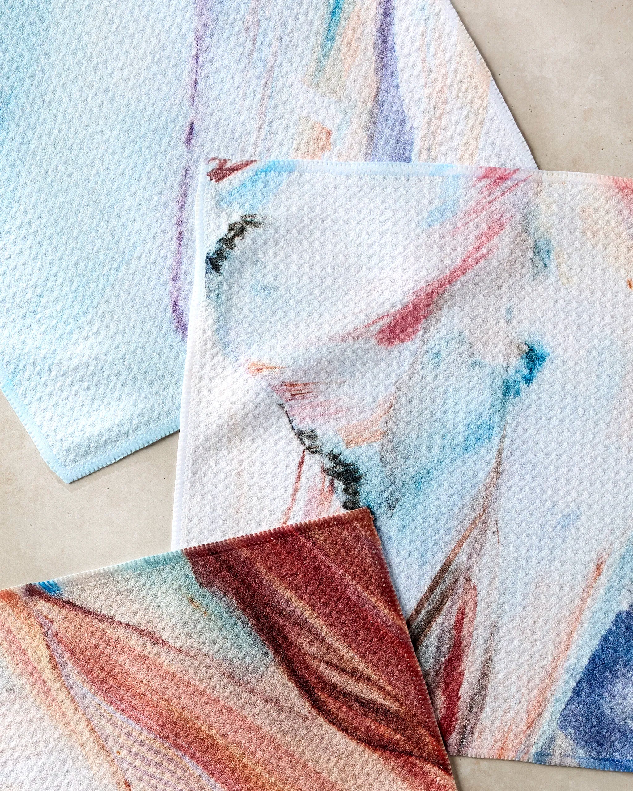 The "Golden Hour in the Rockies" dishtowel set by Kelly Peters features three overlapping, pastel-hued cloths with abstract watercolor designs—a stylish and super-absorbent choice to brighten your kitchen.
