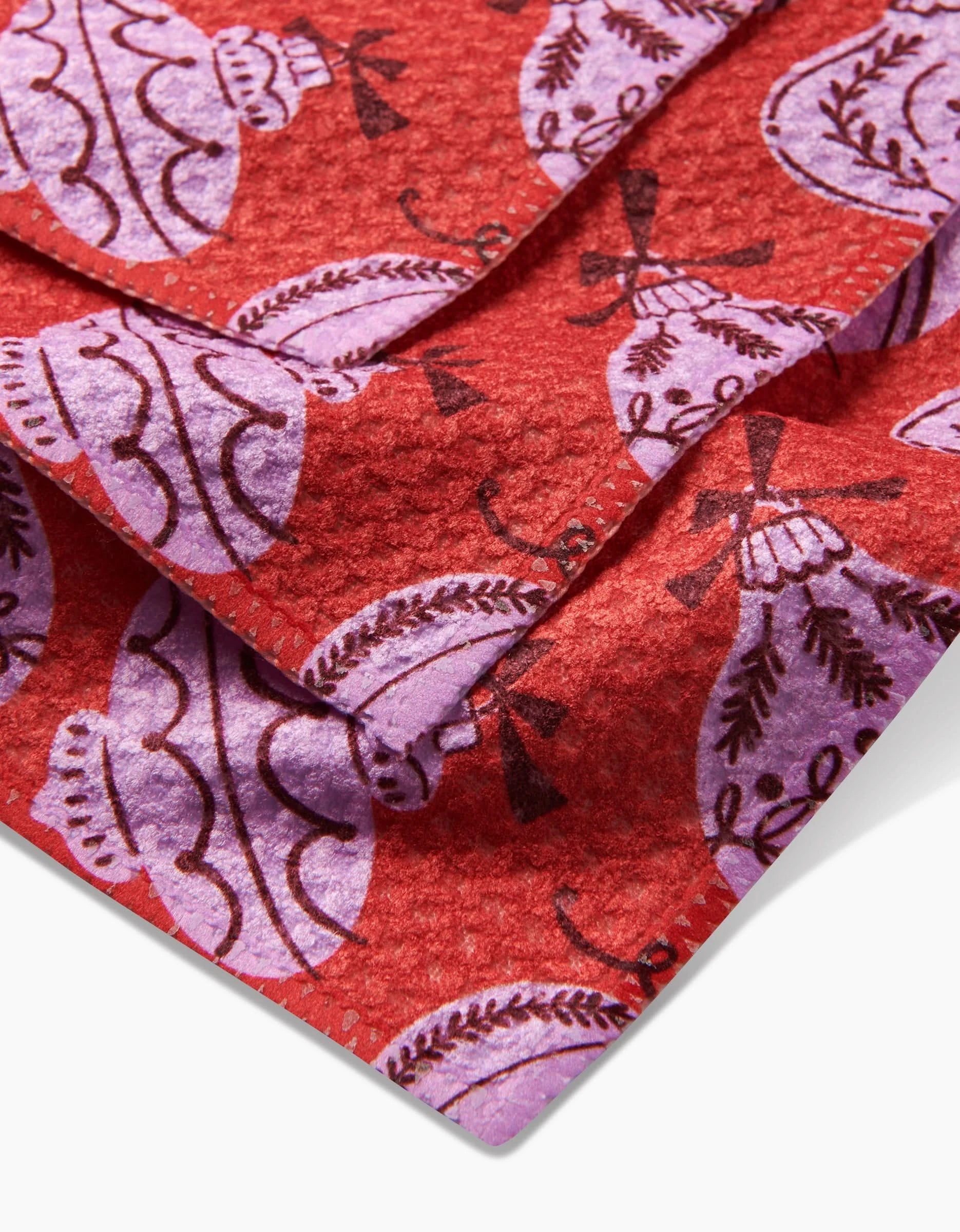 Close-up of Grams Ornaments by Charlie Rowan Designs—red Geoweave fabric with purple and dark red abstract, floral-inspired patterns and overlapping folds. This eco-friendly textile is made from recycled materials.