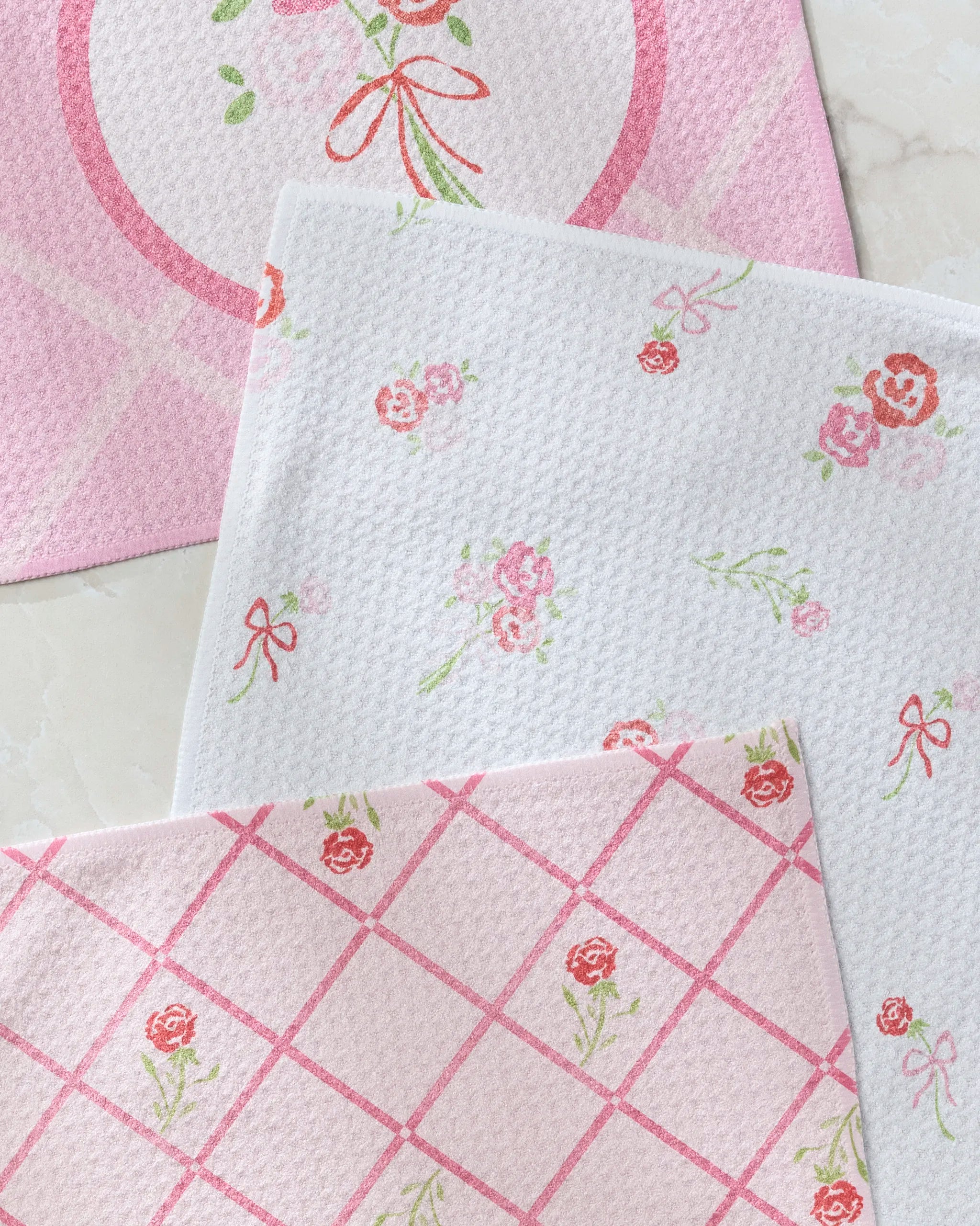 Geometry’s Granny’s Embroidery dishcloth set features three pastel cloths with floral and bow patterns, including grid, scattered flowers, and a circular motif. Each is made from recycled materials for eco-friendly cleaning.
