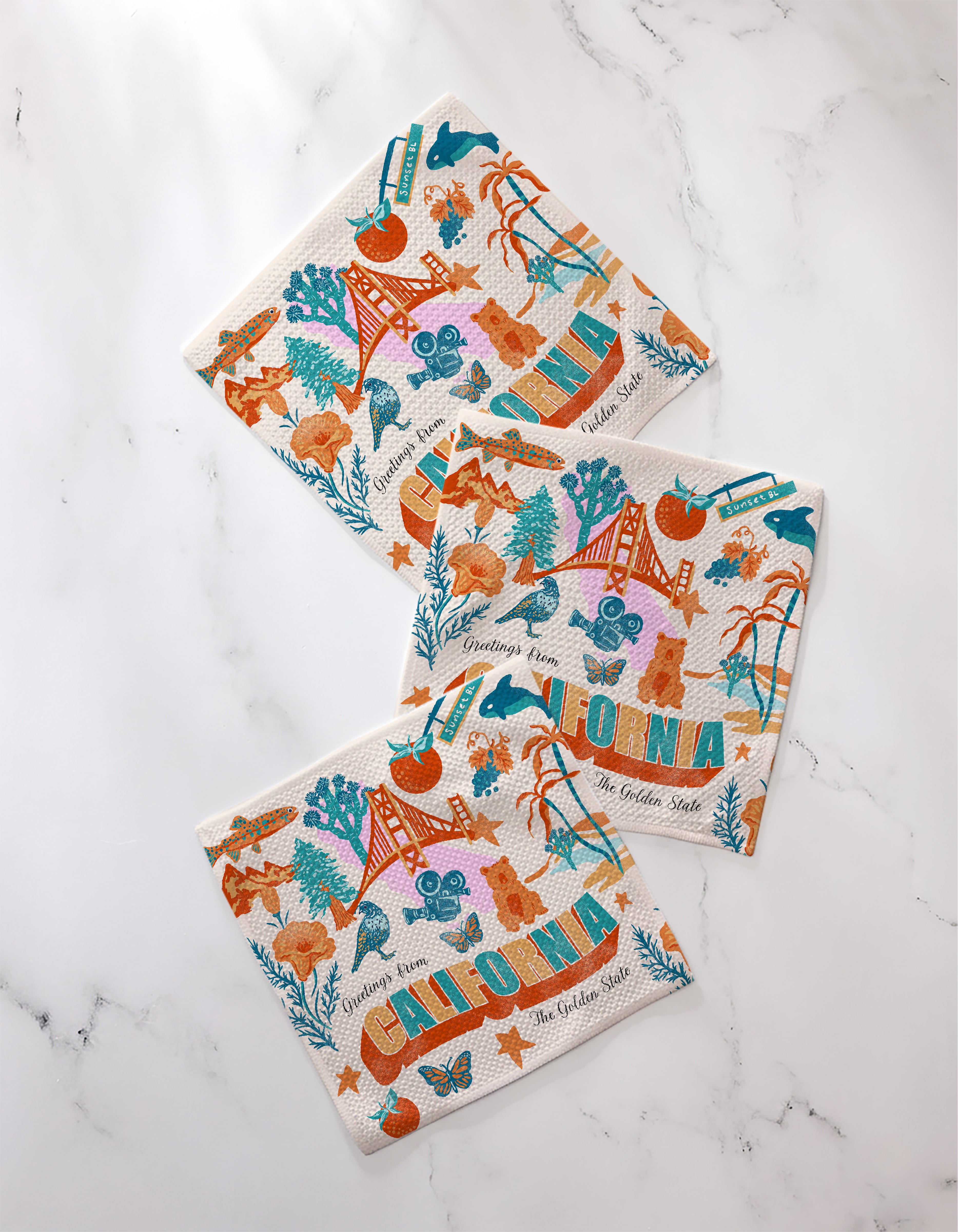 Geometry’s "Greetings From California" napkins feature colorful California-themed illustrations, including the Golden Gate Bridge, bears, oranges, film reels, and bold "California," all made from recycled materials.