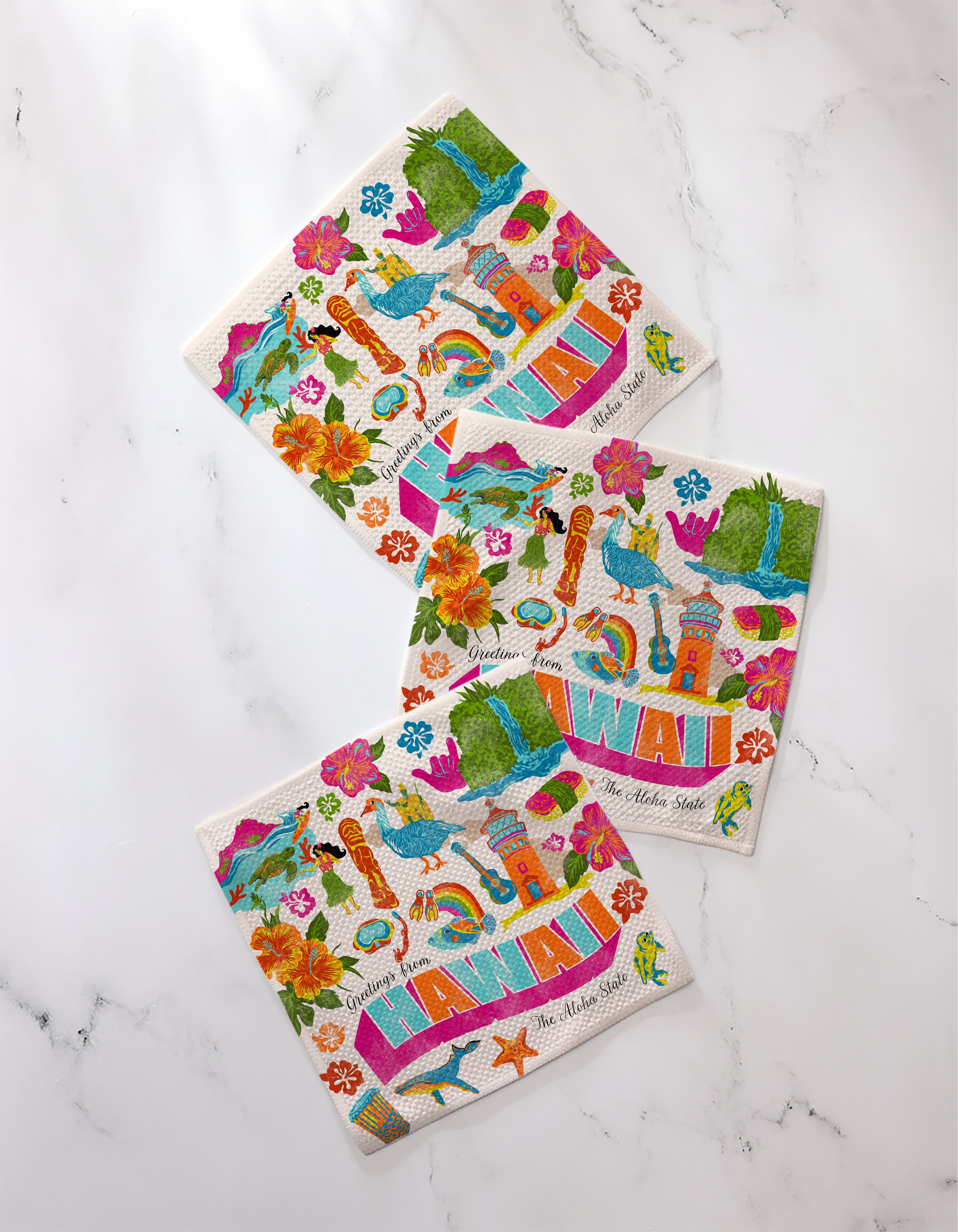 Geometry’s "Greetings From Hawaii" napkins feature vibrant rainbows, hibiscus, pineapples, hula girls, a lighthouse, birds, and palm trees—perfect for pairing with any dishcloth set or super-absorbent dishtowels.
