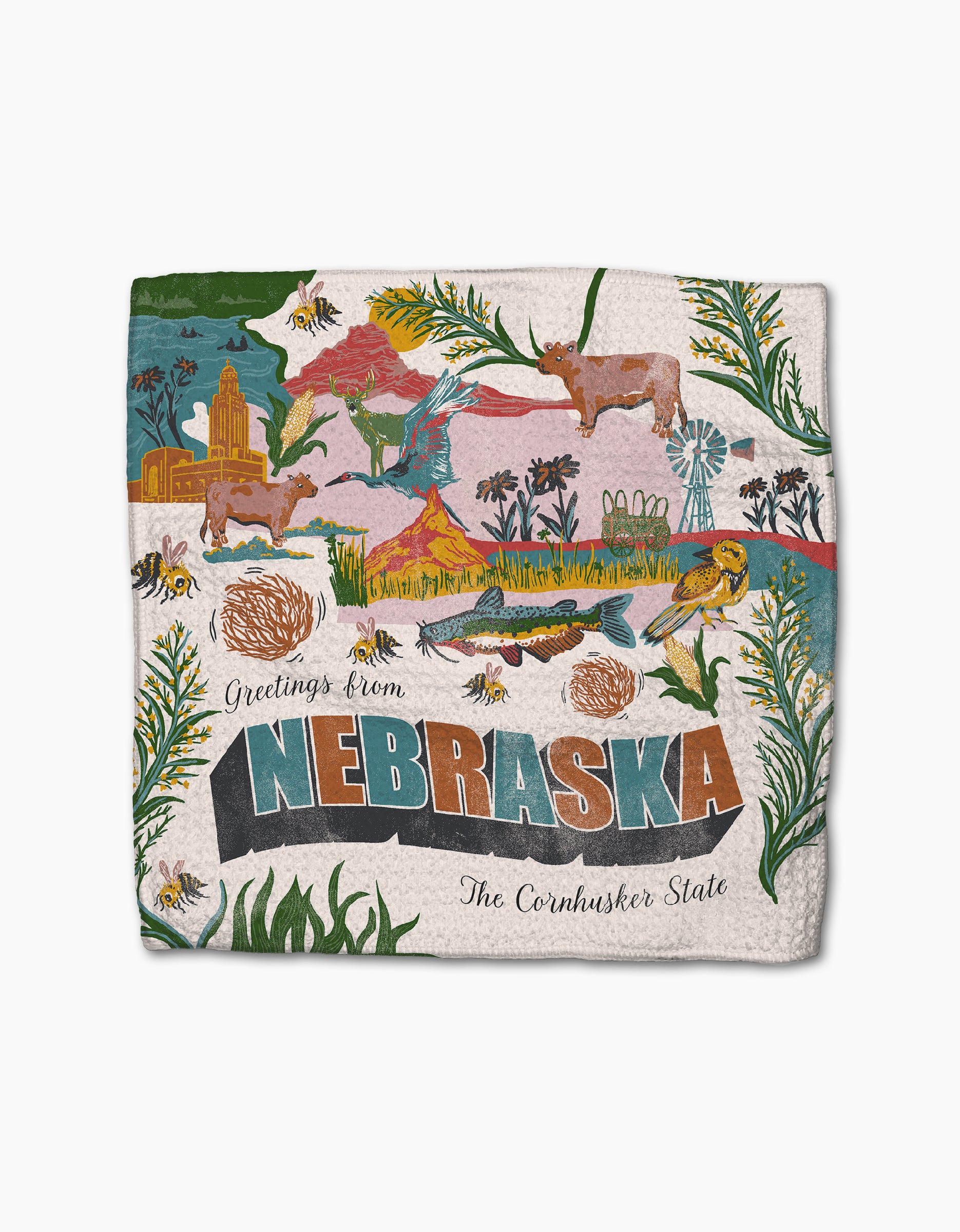 Geometry’s “Greetings From Nebraska” dishcloth set features colorful cows, corn, wildflowers, bees, prairie scenes, a windmill, and city buildings—made from recycled materials with “Greetings from Nebraska” and “The Cornhusker State” text.