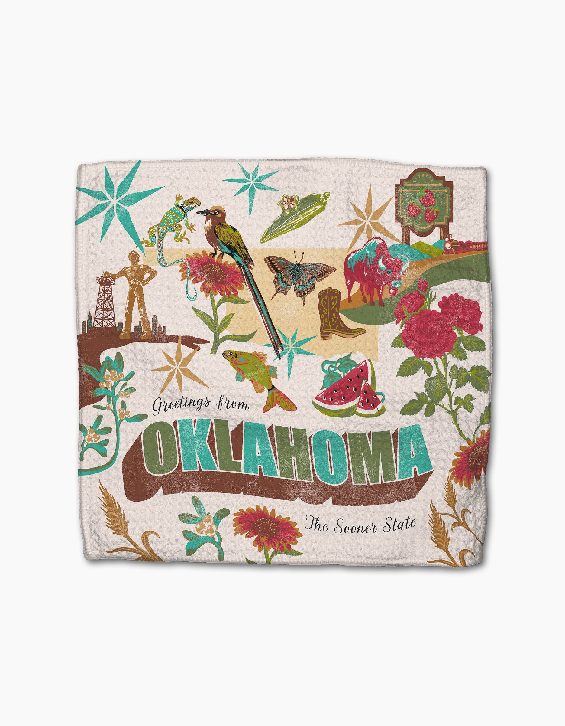 The Geometry “Greetings From Oklahoma” blanket features colorful state symbols—flowers, cowboy boots, a guitar, oil rig, bird, lizard, and watermelon—and is crafted from recycled materials.