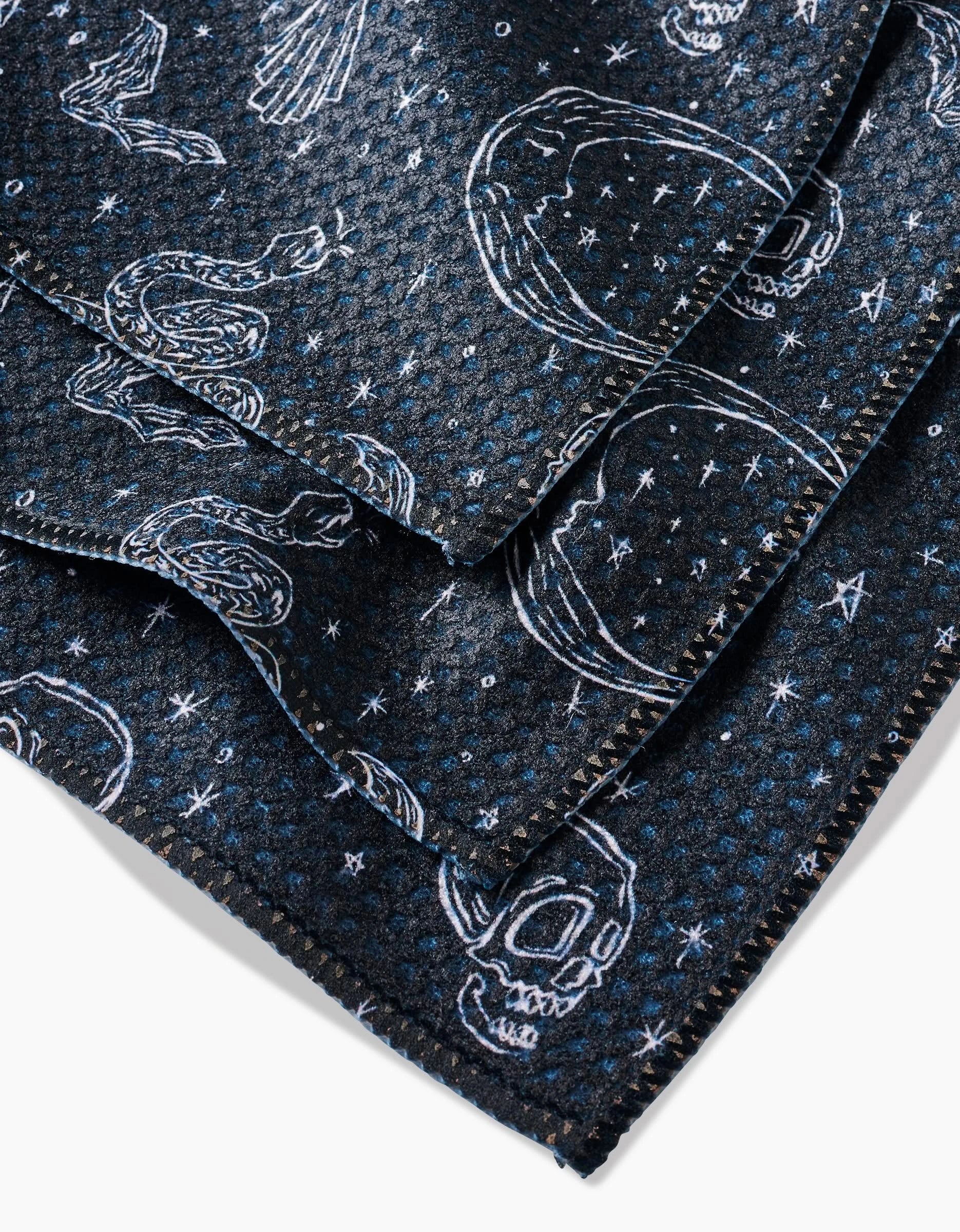 Aubrey Fairchild’s Halloween Hauntings dishcloths feature dark fabric and hand-drawn snakes, skulls, stars, and celestial designs on zigzag edges—crafted from recycled materials for a uniquely eco-friendly touch.