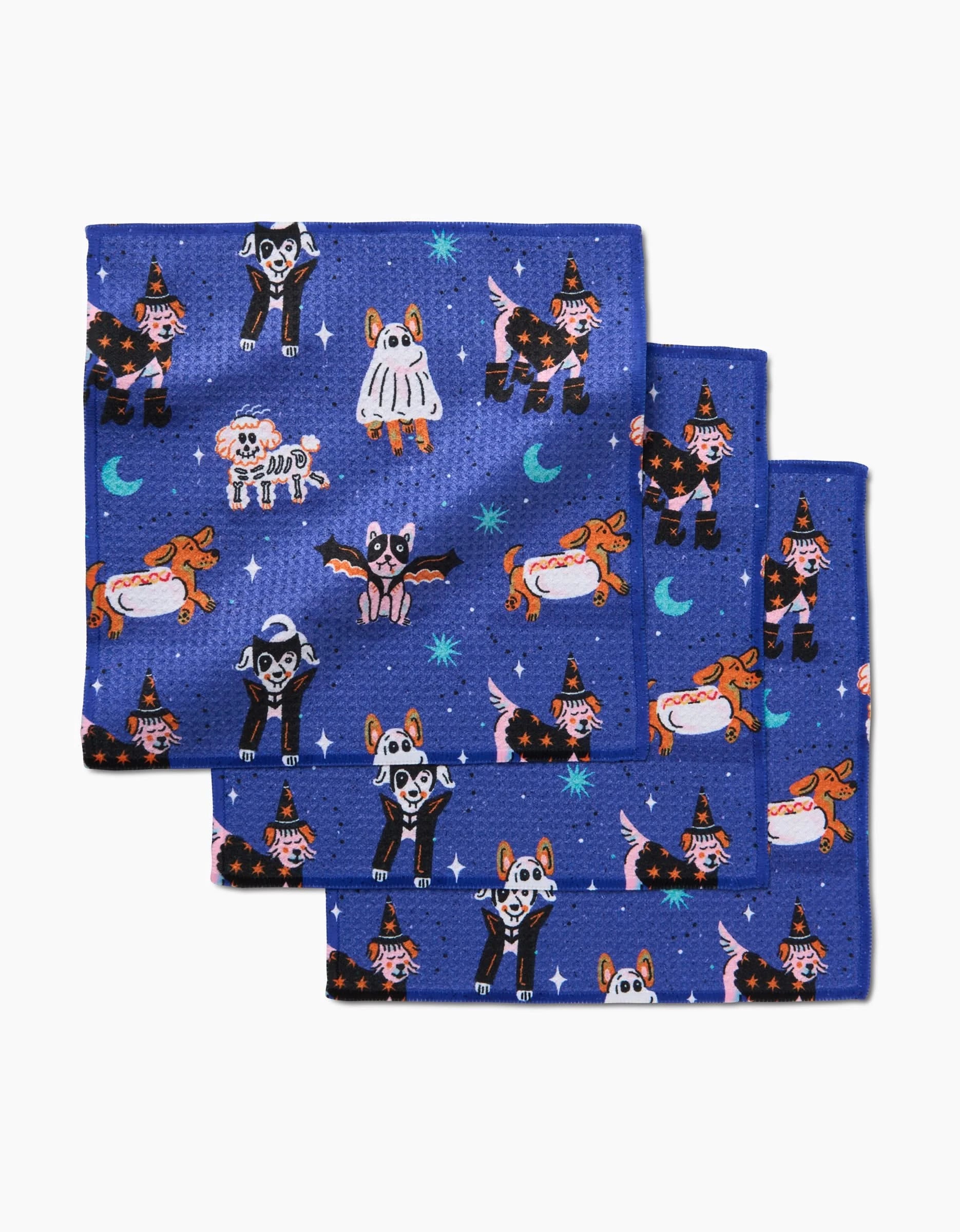 The Camila Leão Halloween Hounds set includes three super-absorbent dish towels featuring dogs in costumes, witches, bats, and moons on a dark blue, starry background—festive and eco-friendly with recycled materials.