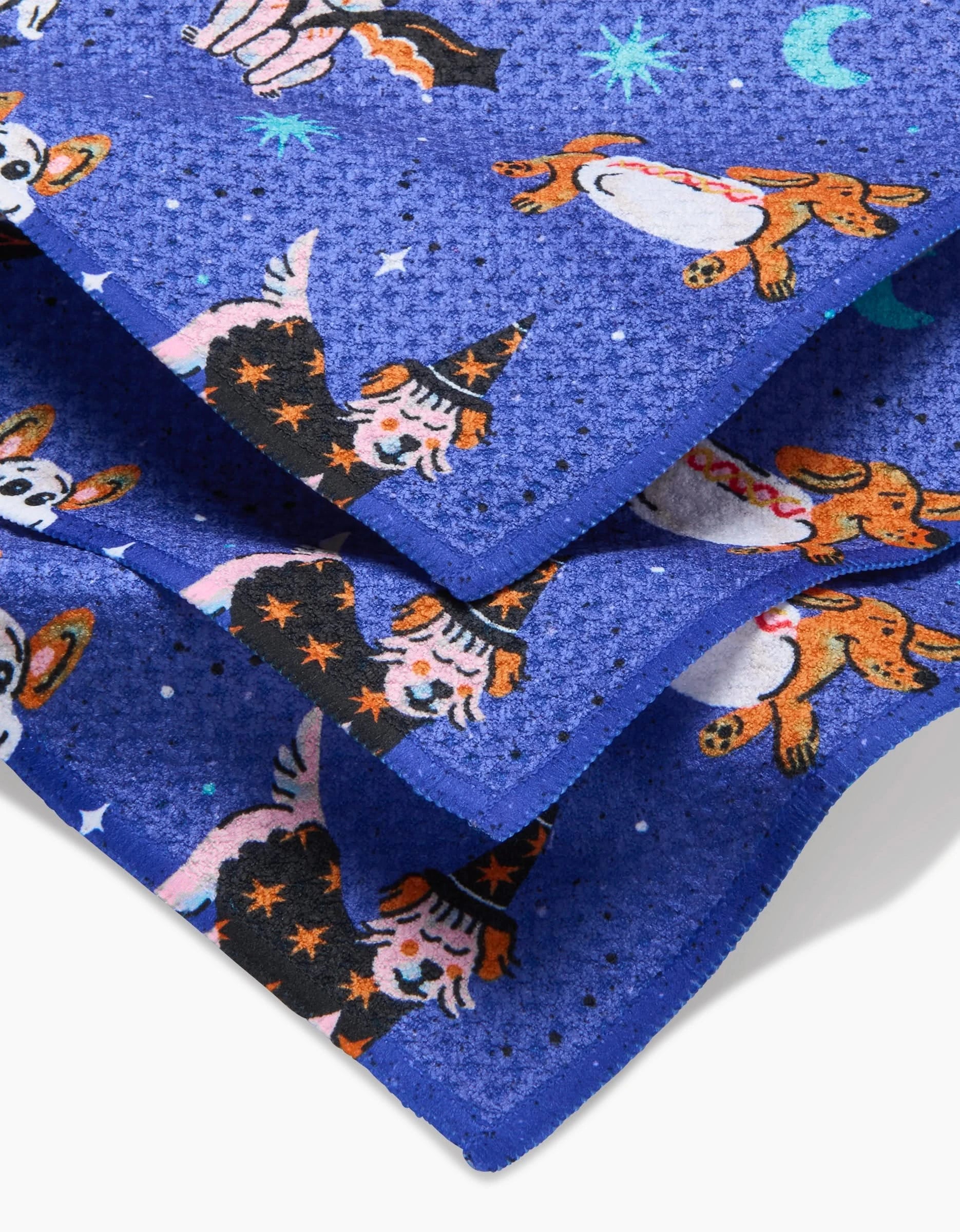 Close-up of Camila Leão’s Halloween Hounds dishcloth set in blue, featuring playful dogs in costumes amid stars and moons, and crafted from recycled materials for an eco-friendly touch.