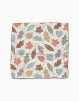 The Harvest Scatter by Sarah Daugherty is a square cloth made from recycled materials, featuring an autumn leaf pattern in muted red, orange, blue, and brown on a cream background.