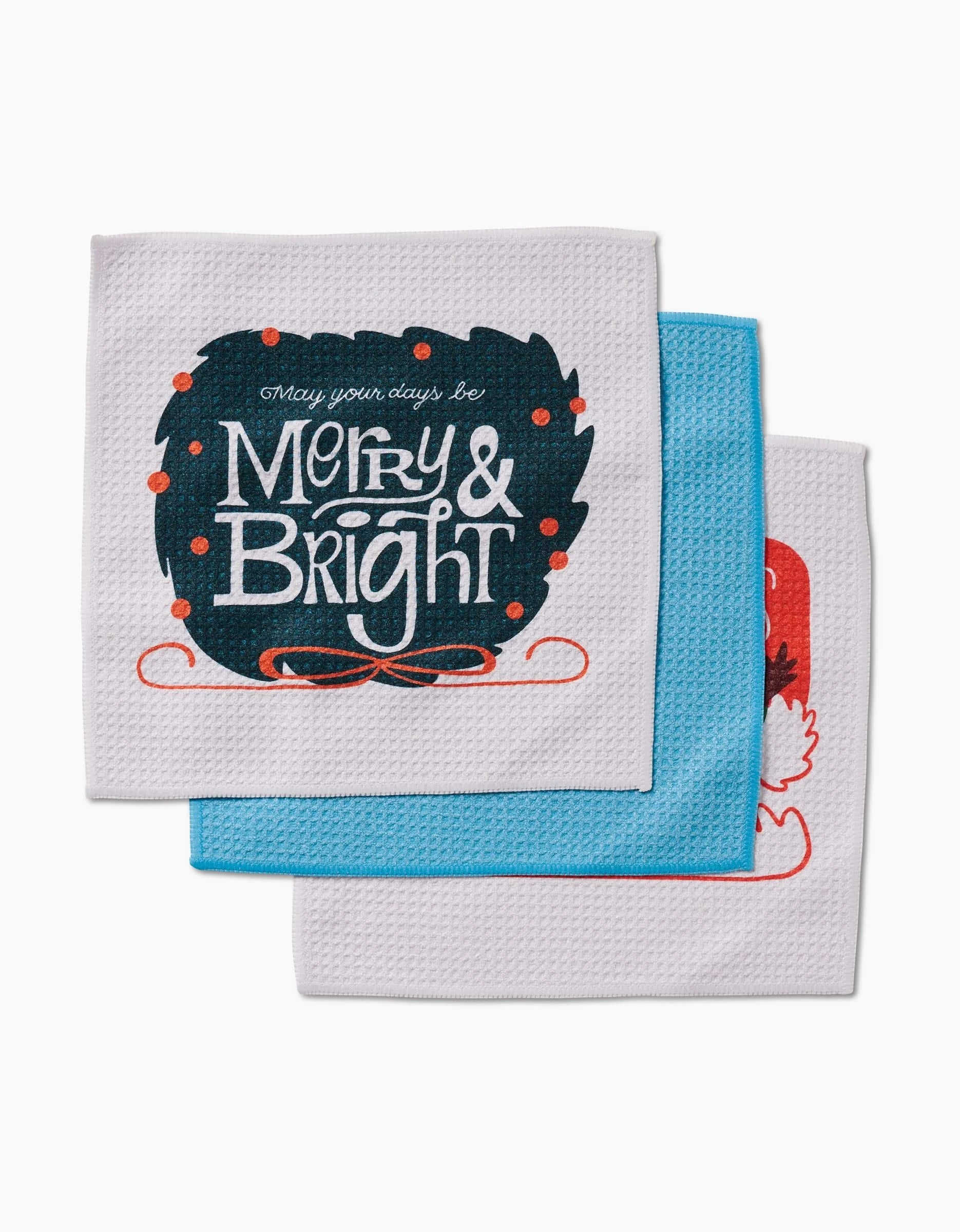 Three folded dish towels by Carly Berry, “Here Comes Santa Claus” collection, in festive Geoweave fabric. The front towel says “may your days be Merry & Bright” on dark blue; the others are partially visible in blue and red.