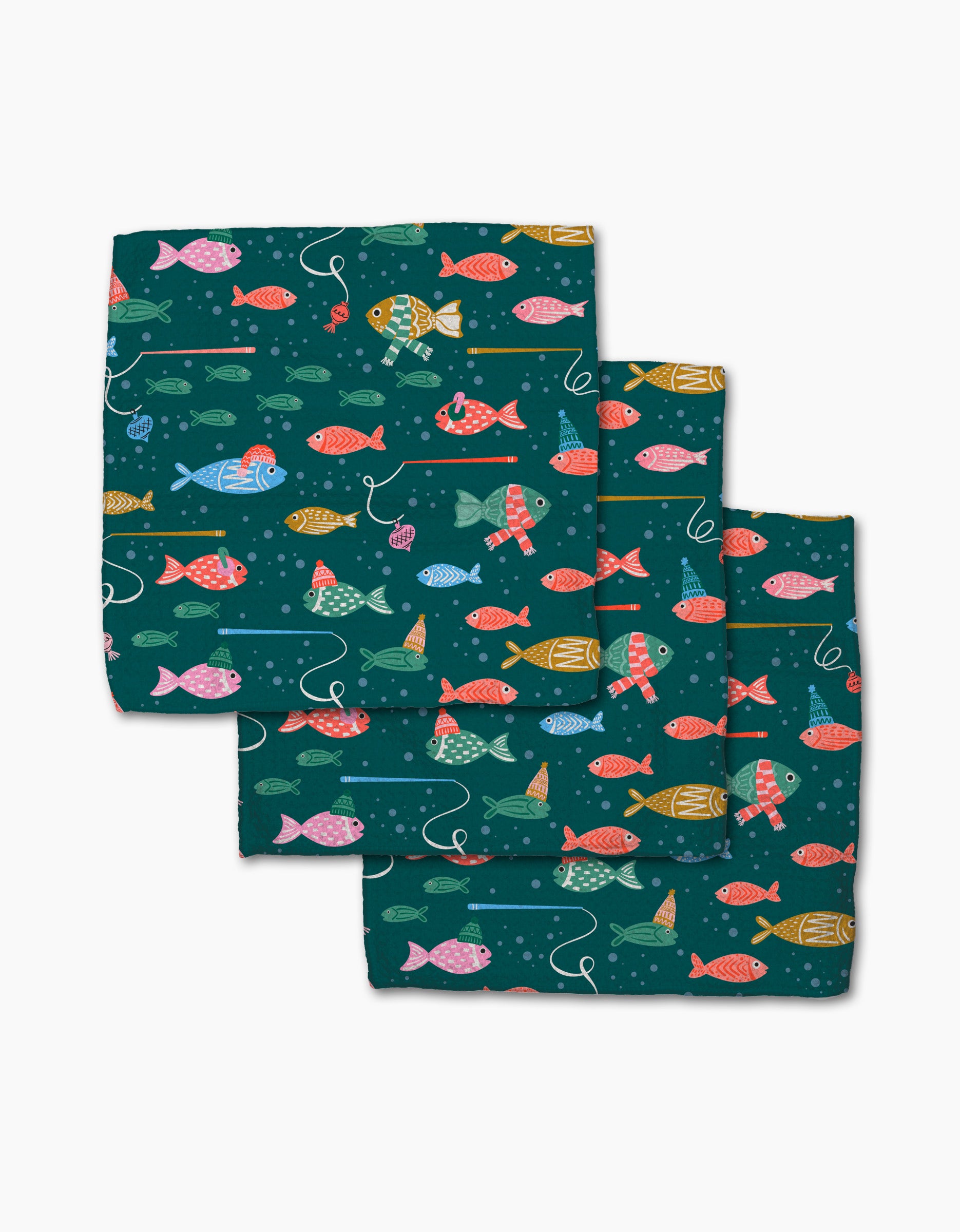 Holiday Fish napkins by Charlie Rowan Designs are made from recycled materials and feature a playful pattern of colorful fish and white fishing lines on a dark teal background. The set includes three cloth napkins.