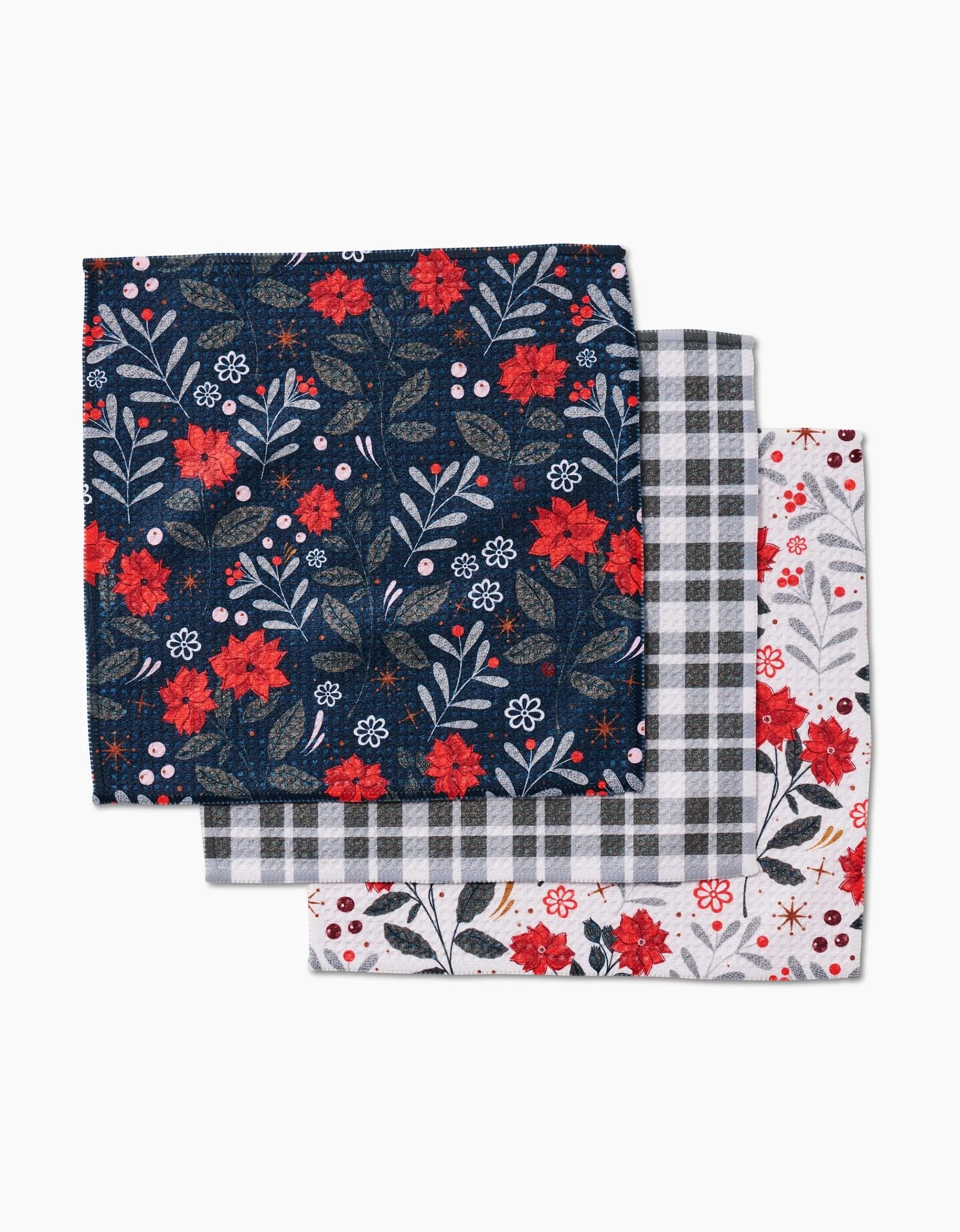 Three folded napkins from Charlie Rowan Designs Holiday Floral collection: top—dark blue with red and white florals, middle—gray and white plaid, bottom—white dishcloth with small red and black floral print.