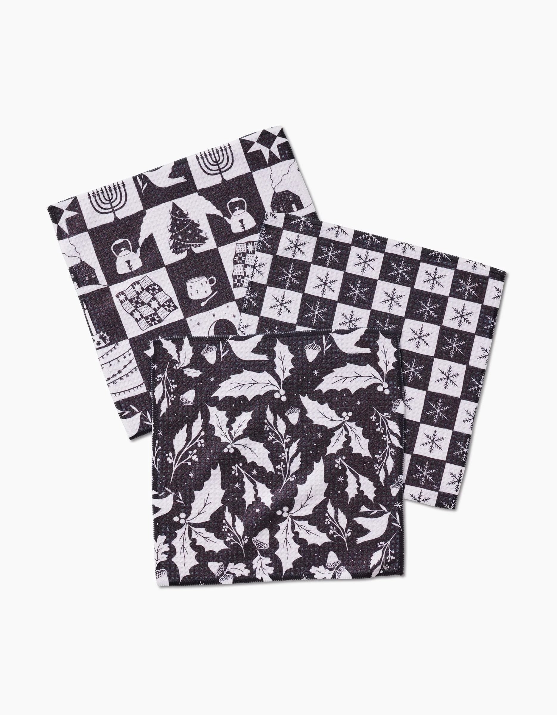 Holiday Love by Elana Gabrielle: three folded recycled cloth napkins with black and white holiday patterns—winter icons grid, holly leaves with berries, and snowflakes with stars—overlapping on a white background.