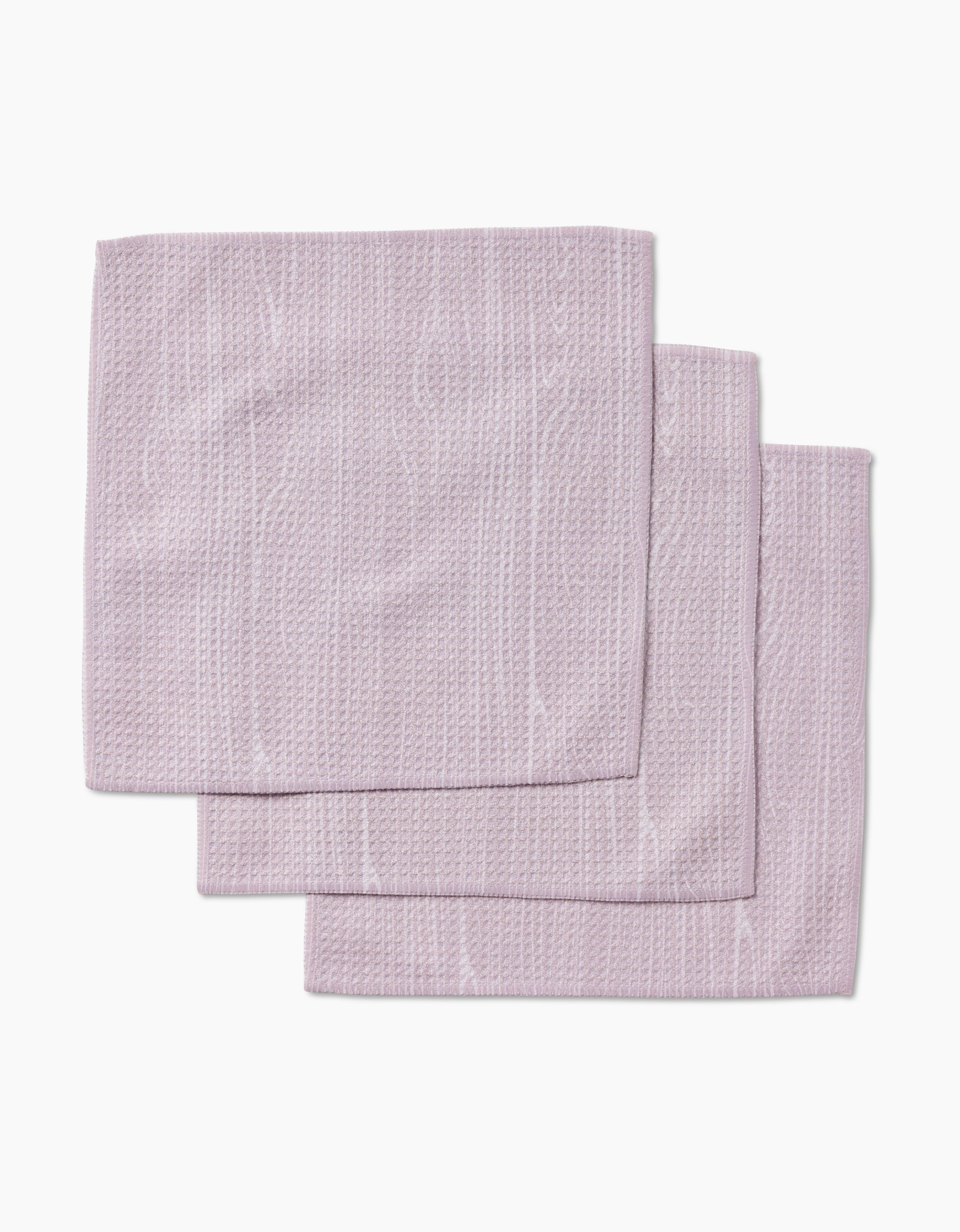 Three folded, textured, light purple Houston Wood dishcloth napkins by Kailee Wright, made from Geoweave fabric, are neatly stacked on a plain white background.