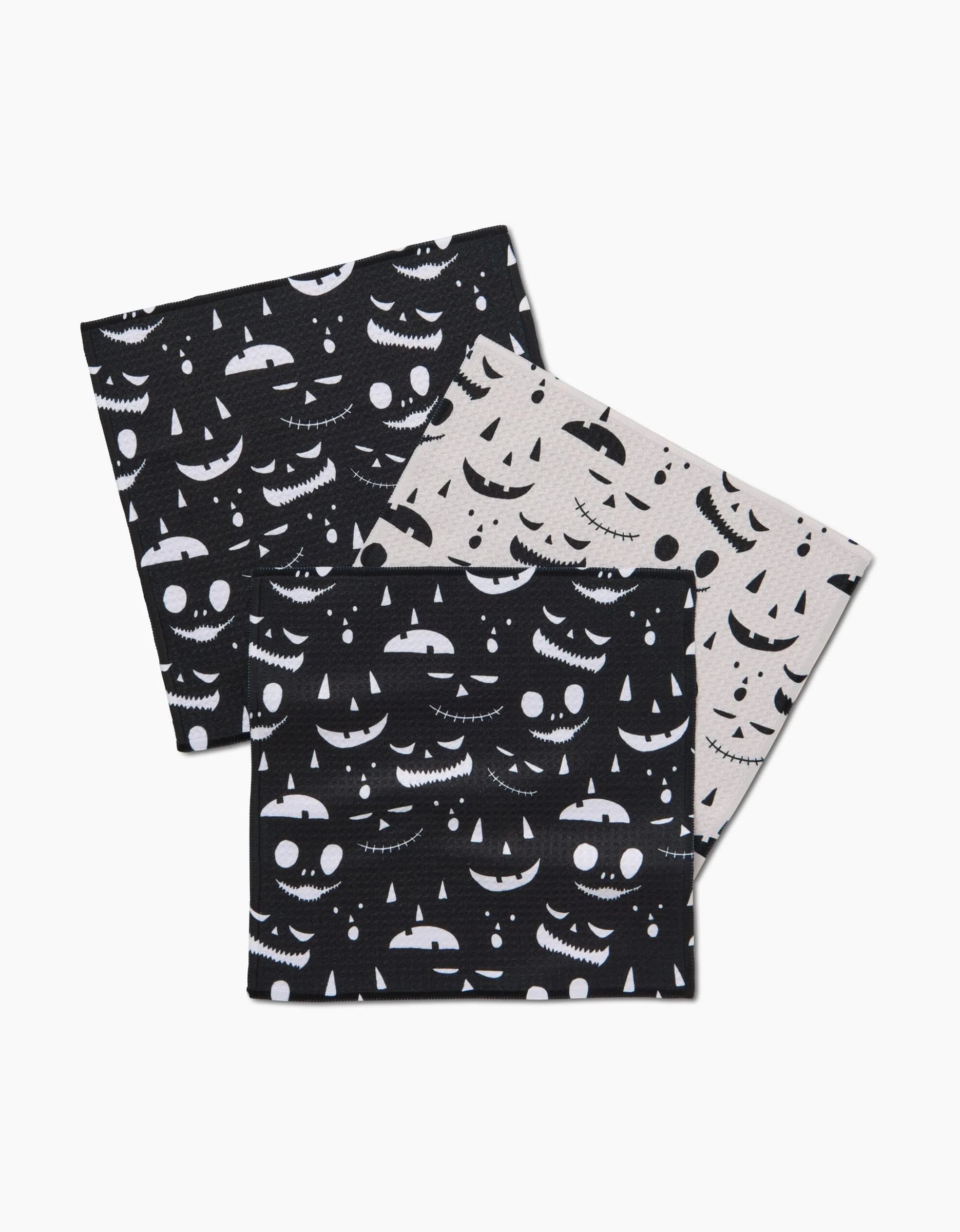 Three folded Danelys Sidron Jack O Lantern Jamboree masks feature white jack-o-lantern faces on black and beige, overlapping on white—festive style that pairs perfectly with recycled dishcloths this season.