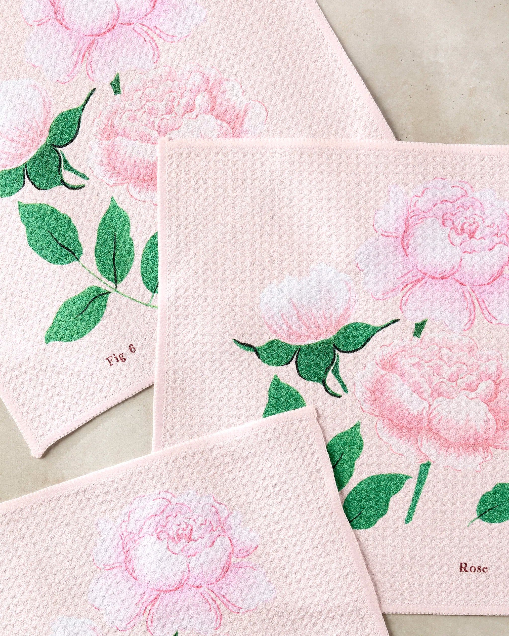 Three pale pink recycled dishcloths from Linda Fox’s June Roses set feature pink peonies, green leaves, and botanical labels Fig 6 and Rose, making them a functional and beautiful addition to your kitchen.