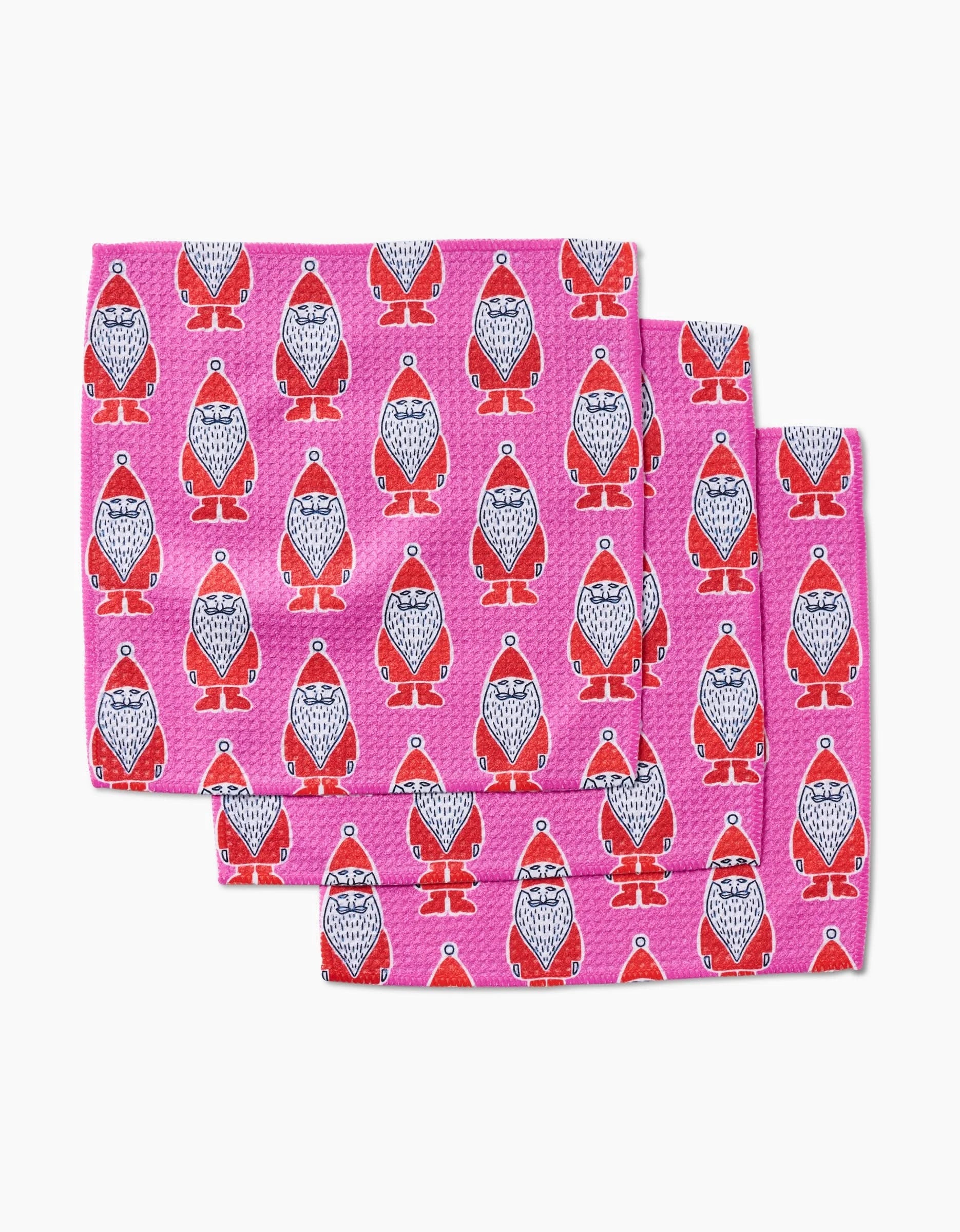 Three folded Klass napkins by Amy MacCready, made from Geoweave fabric and decorated with red and white penguins in hats, are arranged in a staggered stack on a white background.