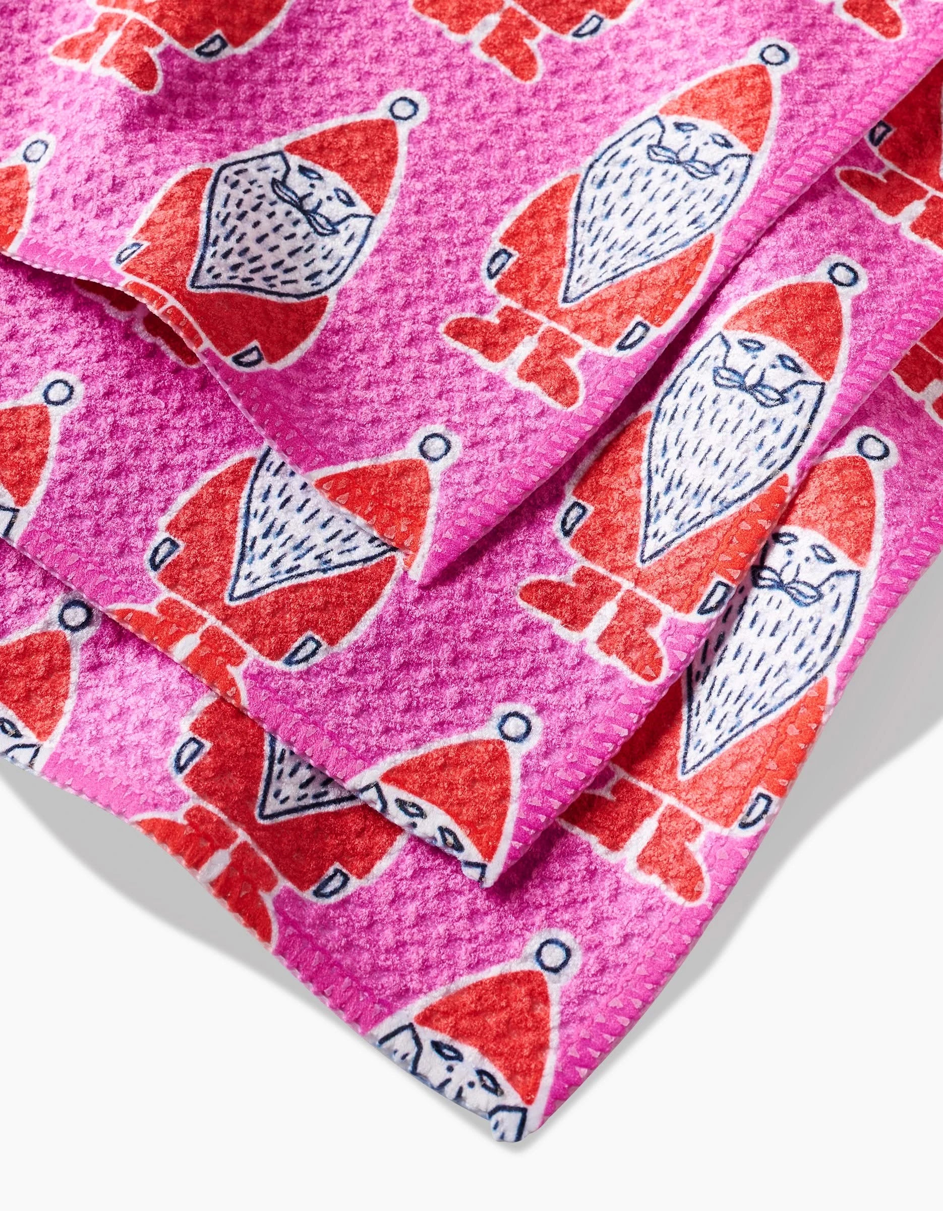 Close-up of pink Klass Geoweave fabric by Amy MacCready, featuring a repeating pattern of cartoon Santa Claus figures—red suits, hats, white beards, and smiles—ideal for festive dishcloths.