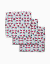 Three white dishcloth napkins from Second Nature Studio’s Ladybug Dance, made with Geoweave fabric and featuring a playful pattern of red and blue ladybugs and blue geometric stars, are shown slightly overlapping on a white background.