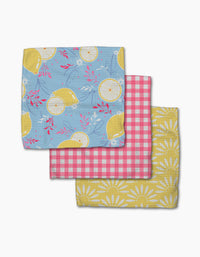 Ashley Celena’s Lemon Pop dishcloth set includes three folded napkins: blue with yellow lemons, pink and white gingham, and yellow daisy prints—each super-absorbent for everyday kitchen use.