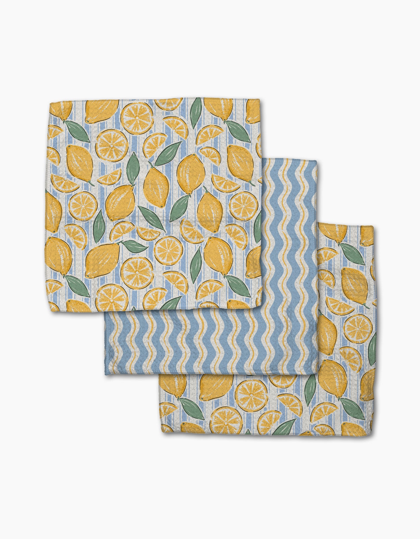The Lemon Waves napkin set by Hufton Studio includes three Geoweave cloth napkins: two with yellow lemons, green leaves, and lemon slices on white, and one with blue and white zigzag stripes plus yellow waves.