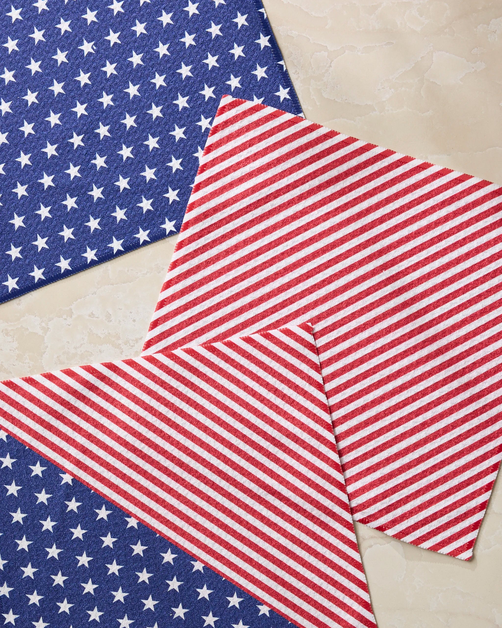 The Liberty dishcloth set by Geometry features blue with white stars and red and white stripes on light marble, evoking the American flag. Made from recycled materials, this eco-friendly set combines style with sustainability.