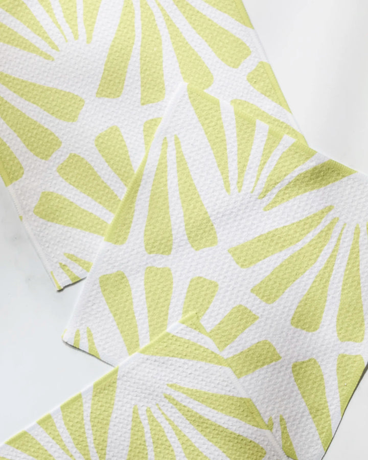 Three white paper napkins from Geometry, featuring the Lime Blossom design with a light green sunburst pattern and textured surface, are arranged on a white background—perfect to pair with recycled dishcloth sets.
