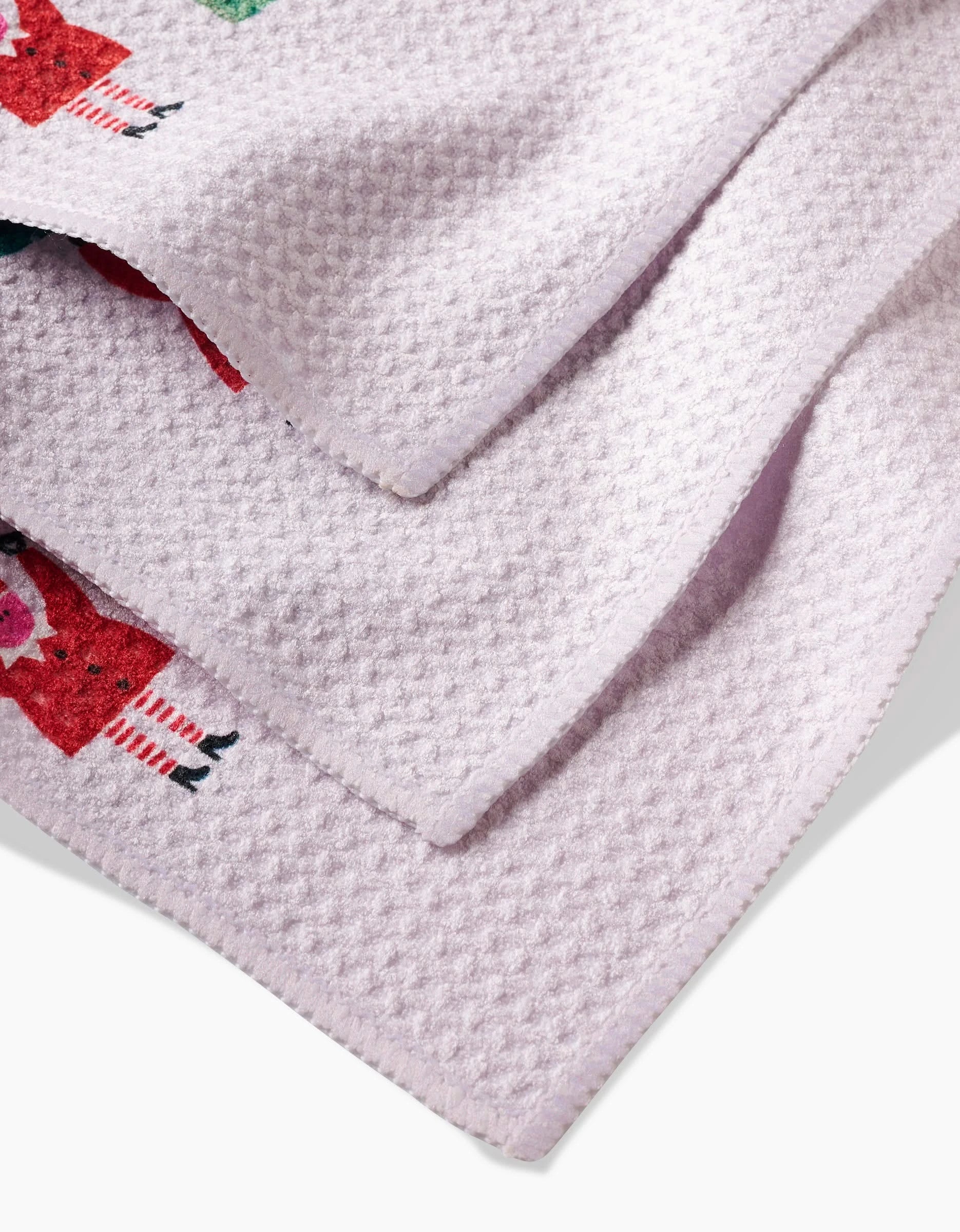 A close-up of the light purple Little Helpers dishcloth by Daria Solak, made from Geoweave fabric with a waffle weave and featuring colorful cartoon animal designs near the edge.