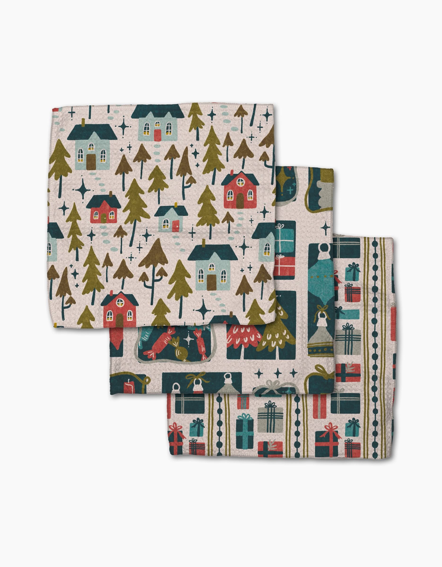 Little Village by Amy MacCready: a set of three folded holiday cloth napkins made from recycled materials, featuring festive houses, decorated trees, and wrapped gifts in red, green, blue, and gold on beige.