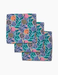 The Lucky Pomegranate napkins by Masha Volnova are made from absorbent recycled materials and feature a vibrant teal, pink, orange, and yellow pomegranate and leaf pattern on a purple background. Set of three.