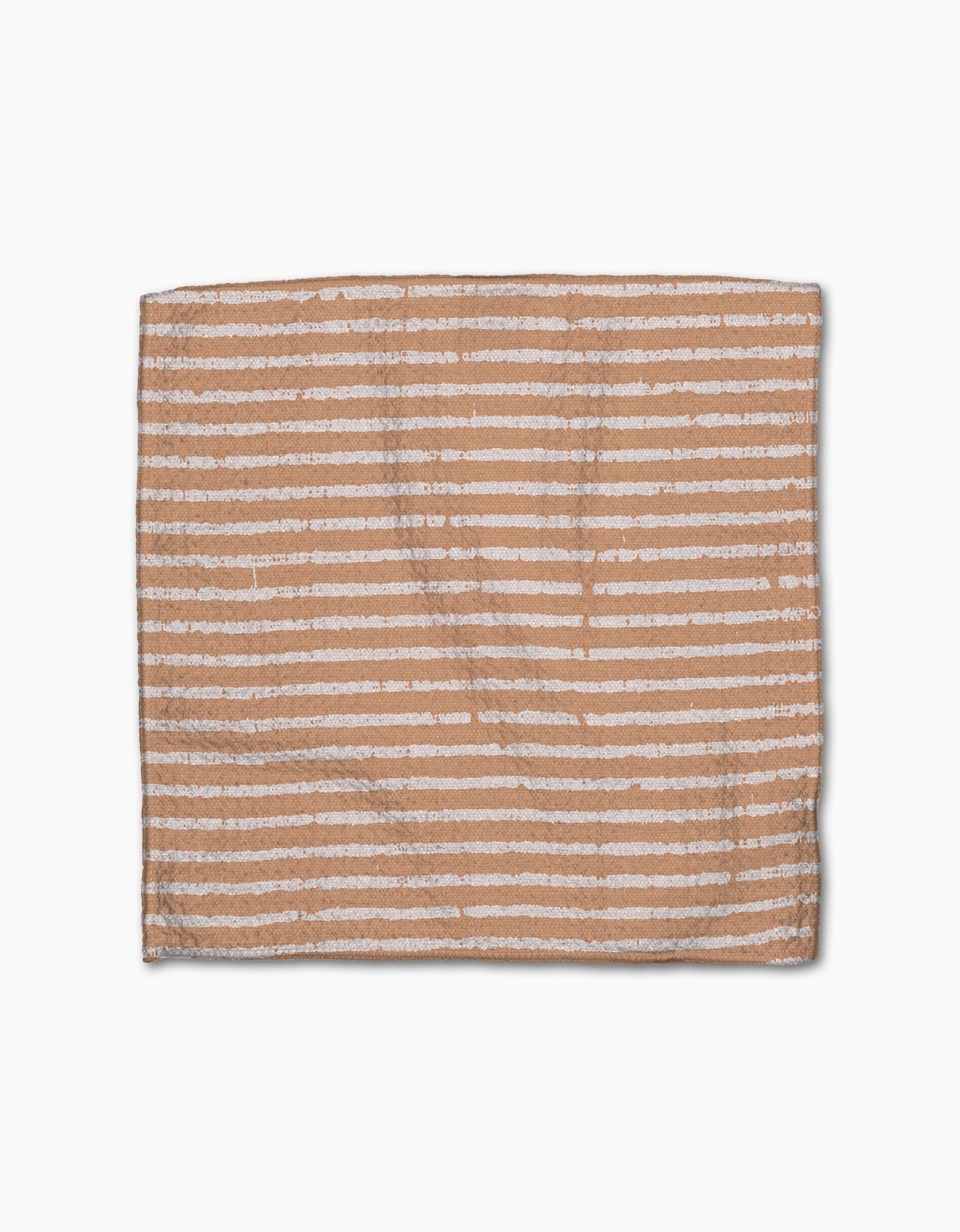 The Geometry Maceta is a rectangular light brown dishcloth made from recycled materials, featuring evenly spaced uneven horizontal white stripes, displayed on a white background.