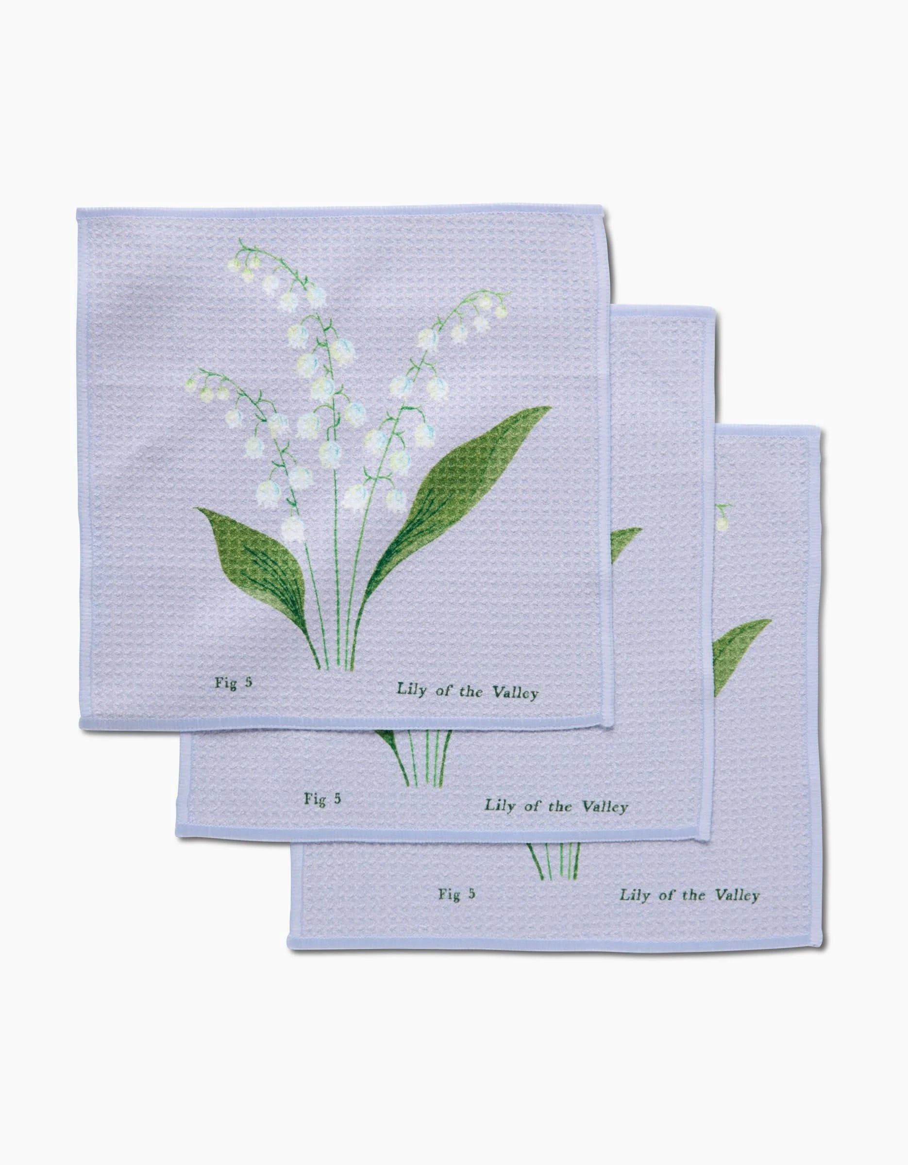 Three light blue May Lilly Of The Valley dishcloths by Linda Fox, made from recycled materials, are stacked, each showing a botanical Lily of the Valley design with green leaves, white flowers, and labeled “Fig 3” or “Fig 5.”.