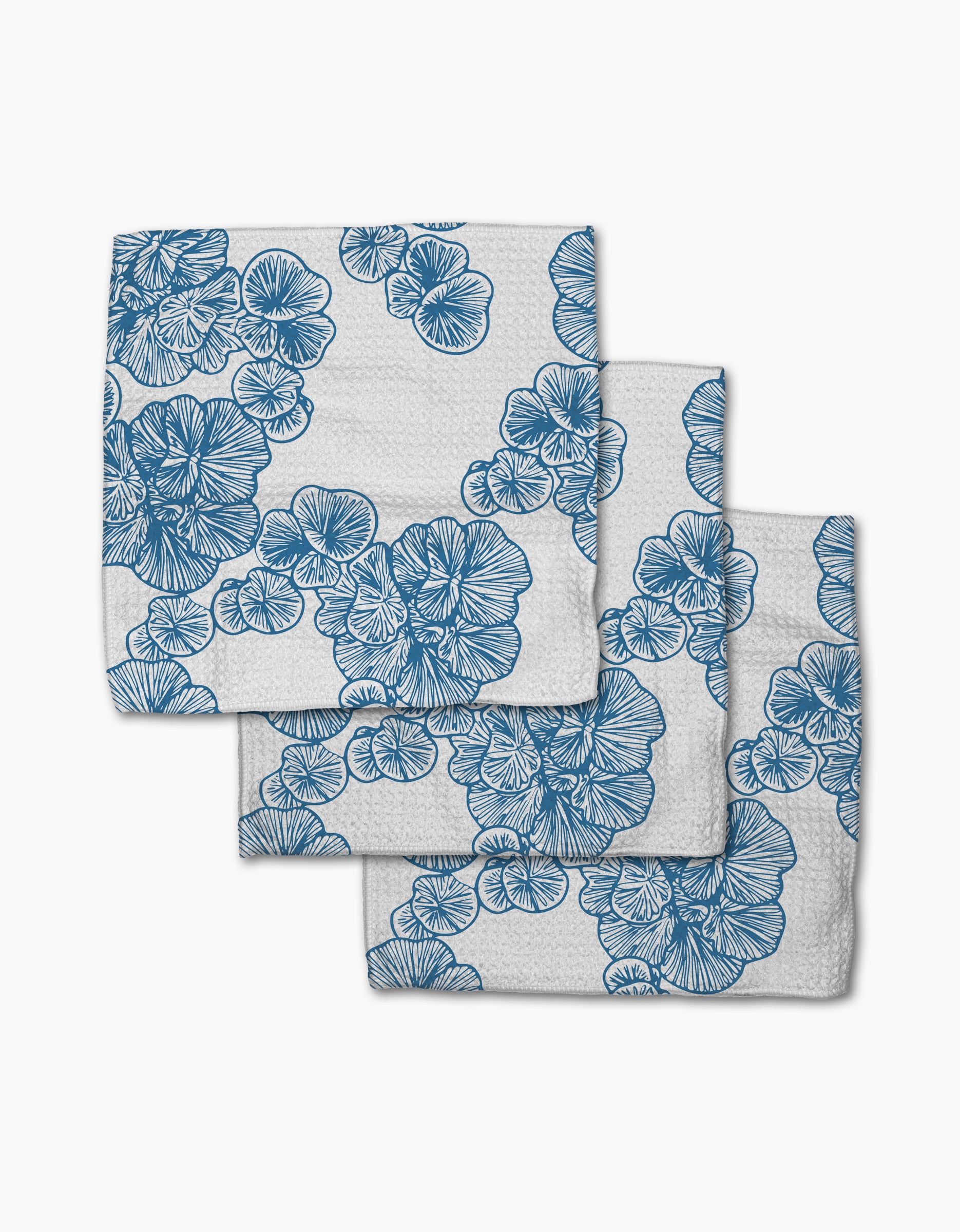 Three Meadowline napkins by Second Nature Studio, made from Geoweave fabric and featuring blue floral patterns with detailed overlapping outlines, are neatly stacked in a slightly offset arrangement on a white background.