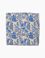 The Mediterranean Pour dishcloth set by Lisa Nelson is beige, made from recycled materials, and features a super-absorbent cloth adorned with a blue pattern of decorative bottles, leaves, and branches covering the entire surface.