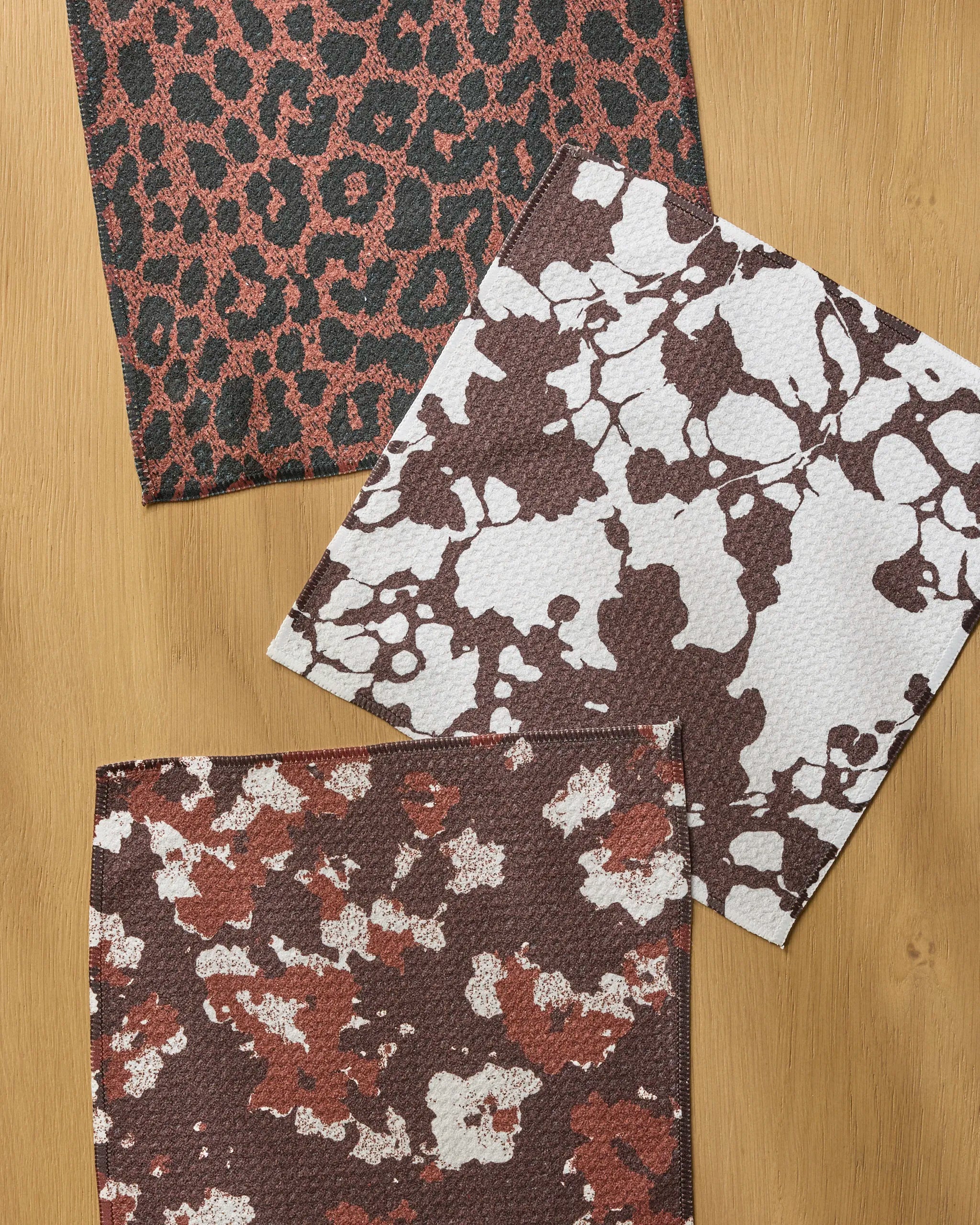 The Geometry Midnight Vine Noir set includes three recycled fabric dishcloths in unique prints, combining super-absorbent function with stylish leopard, cow, and abstract designs for eco-friendly, effective kitchen cleanup.