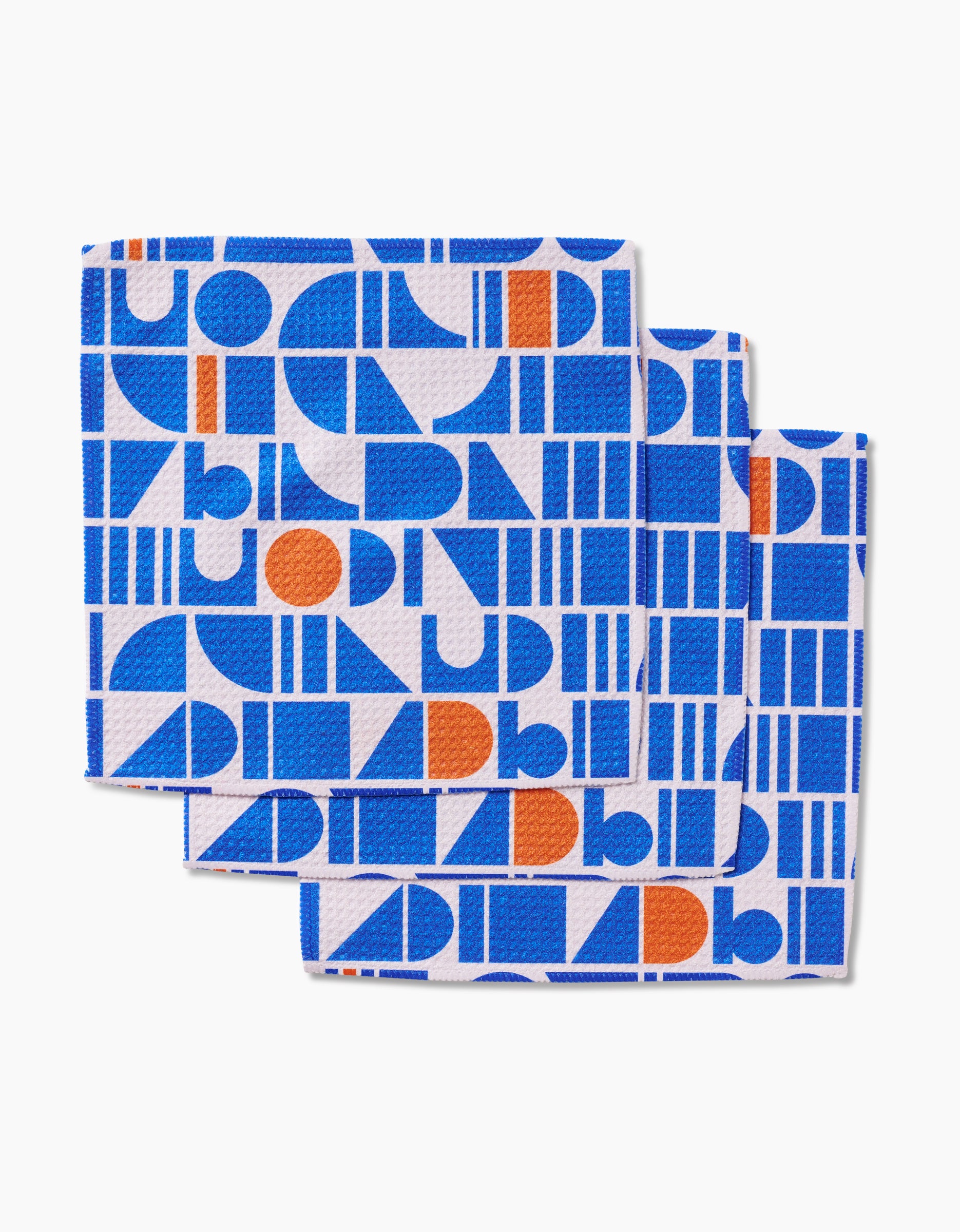 The Misty Oasis dishcloth set by Happy Hemera features three overlapping Geoweave cloths with blue and orange geometric shapes—rectangles, circles, and semicircles—arranged in a modern grid on white.