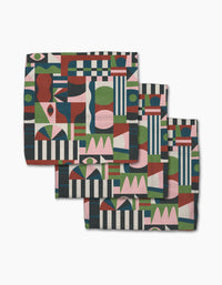 Three stacked Modern Bauhaus Mood cloth napkins by Claire Iglesias, made from Geoweave fabric, feature a colorful pattern of rectangles, circles, stripes, and abstract shapes in red, green, blue, pink, black, and white.