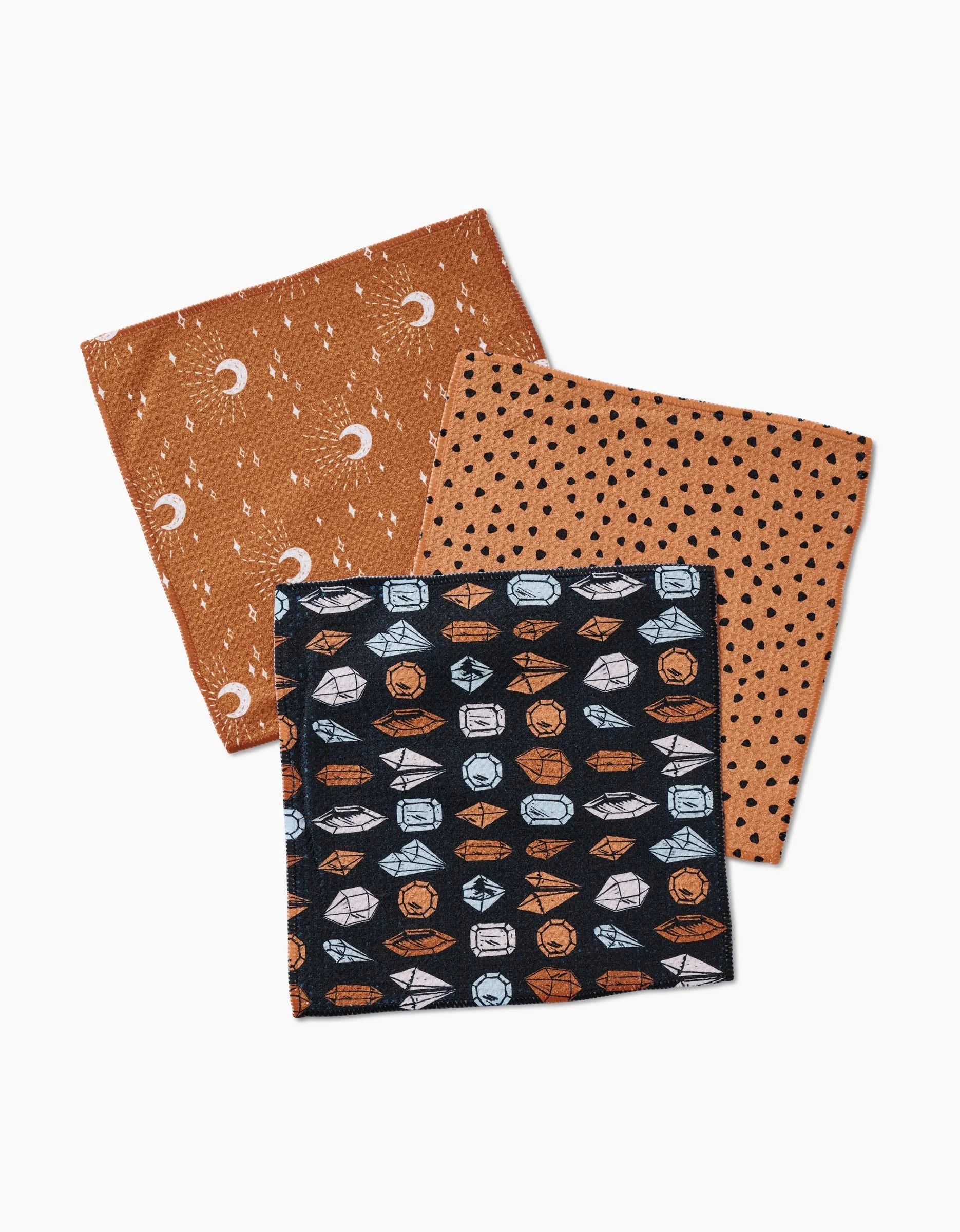 Three folded Moon Craft dishcloths by Hufton Studio are shown: eco-friendly Geoweave fabric, one orange with moons/stars, one orange with black dots, and one black with white and orange geometric patterns.