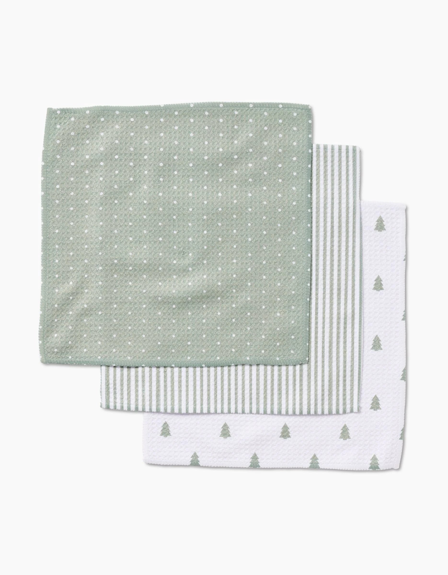 Three folded Noel dishcloths by Kailee Wright are stacked: the top is green with white dots, the middle has green and white stripes, and the bottom is white with small green pine trees—all made from durable Geoweave fabric.