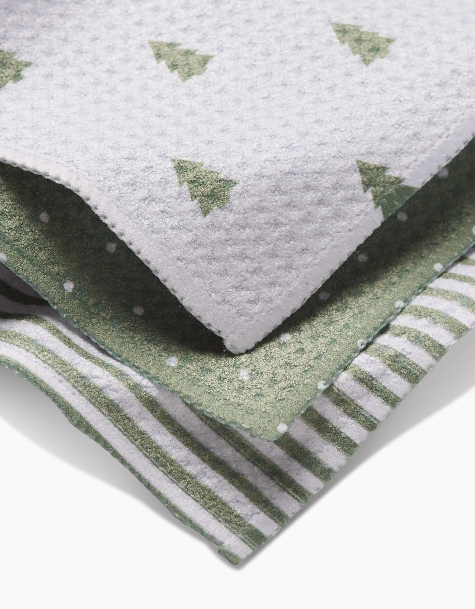 The Noel dishcloth set by Kailee Wright includes three folded cloths in green and white—tree print, polka dots, and stripes—all made from recycled materials.