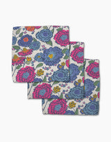 The Painterly Meadow dishcloth set by Kris Ruff includes three colorful cloth napkins made from recycled materials, featuring bold blue, pink, and purple flowers with green leaves on a light background.