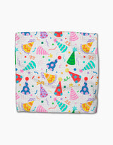 Party Pop by Vaishali Design Studio is a folded white blanket made from eco-friendly Geoweave fabric, featuring pink, blue, green, and yellow party hats with stars, confetti, and streamers scattered across the surface.