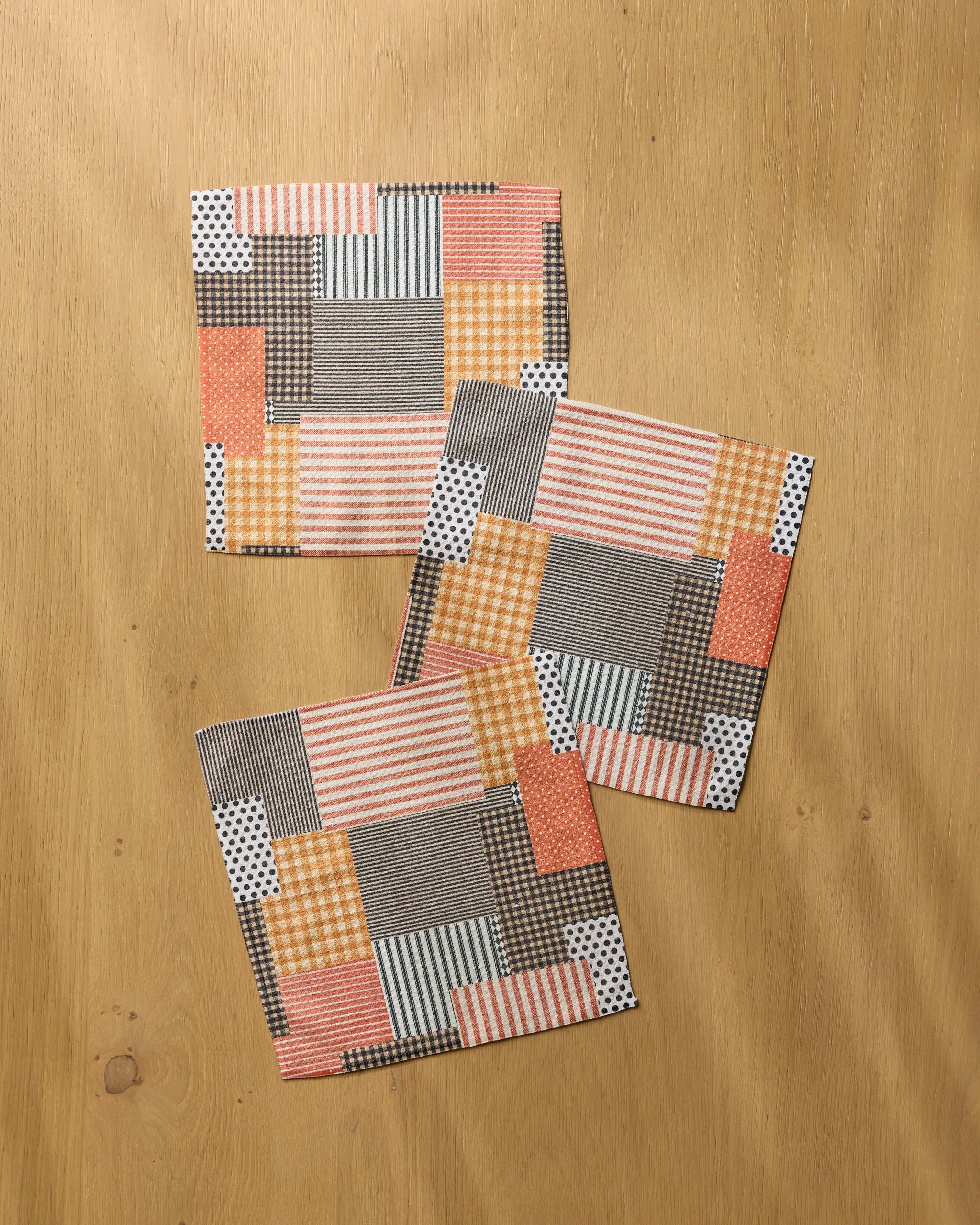 Geometry’s Patch and Pumpkin set features three square fabric coasters with orange, yellow, black, white, and gray patchwork designs—perfect for pairing with any eco-friendly dishcloths or absorbent kitchen towels.