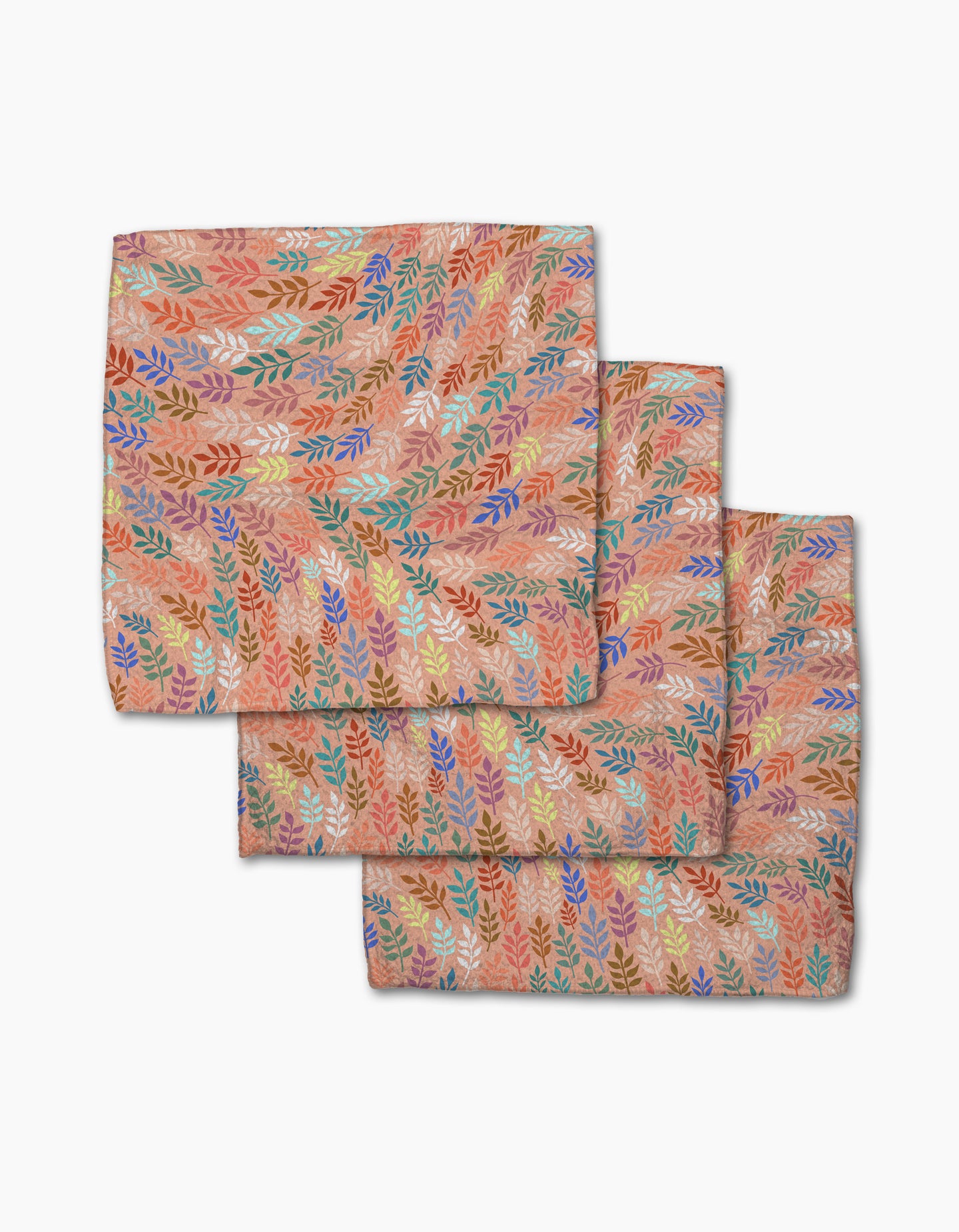 Three folded Peachy Leaf Swirl napkins from Rachel Parker, featuring a multicolored leaf pattern on peach, are stacked on white—a stylish and eco-friendly addition to any dishcloth set.
