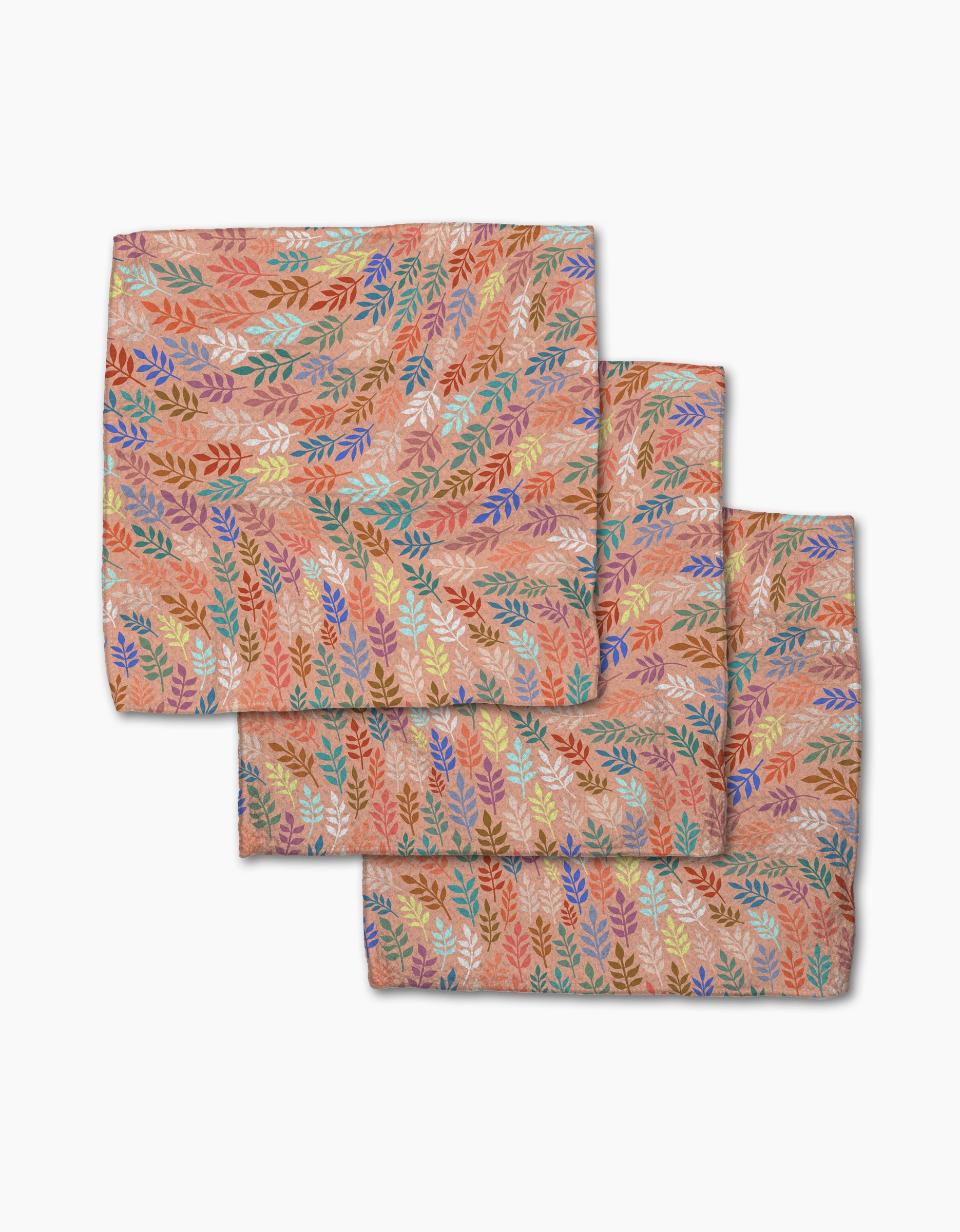Three folded Peachy Leaf Swirl napkins from Rachel Parker, featuring a multicolored leaf pattern on peach, are stacked on white—a stylish and eco-friendly addition to any dishcloth set.